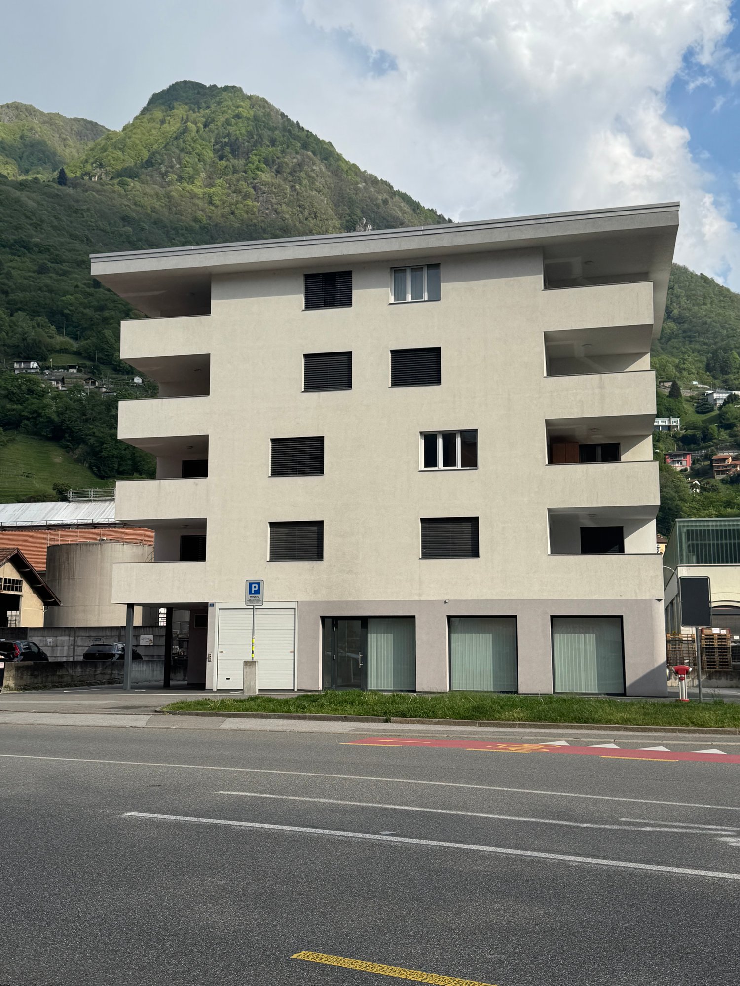 4 story building, white exterior, multiple windows, parking area in front