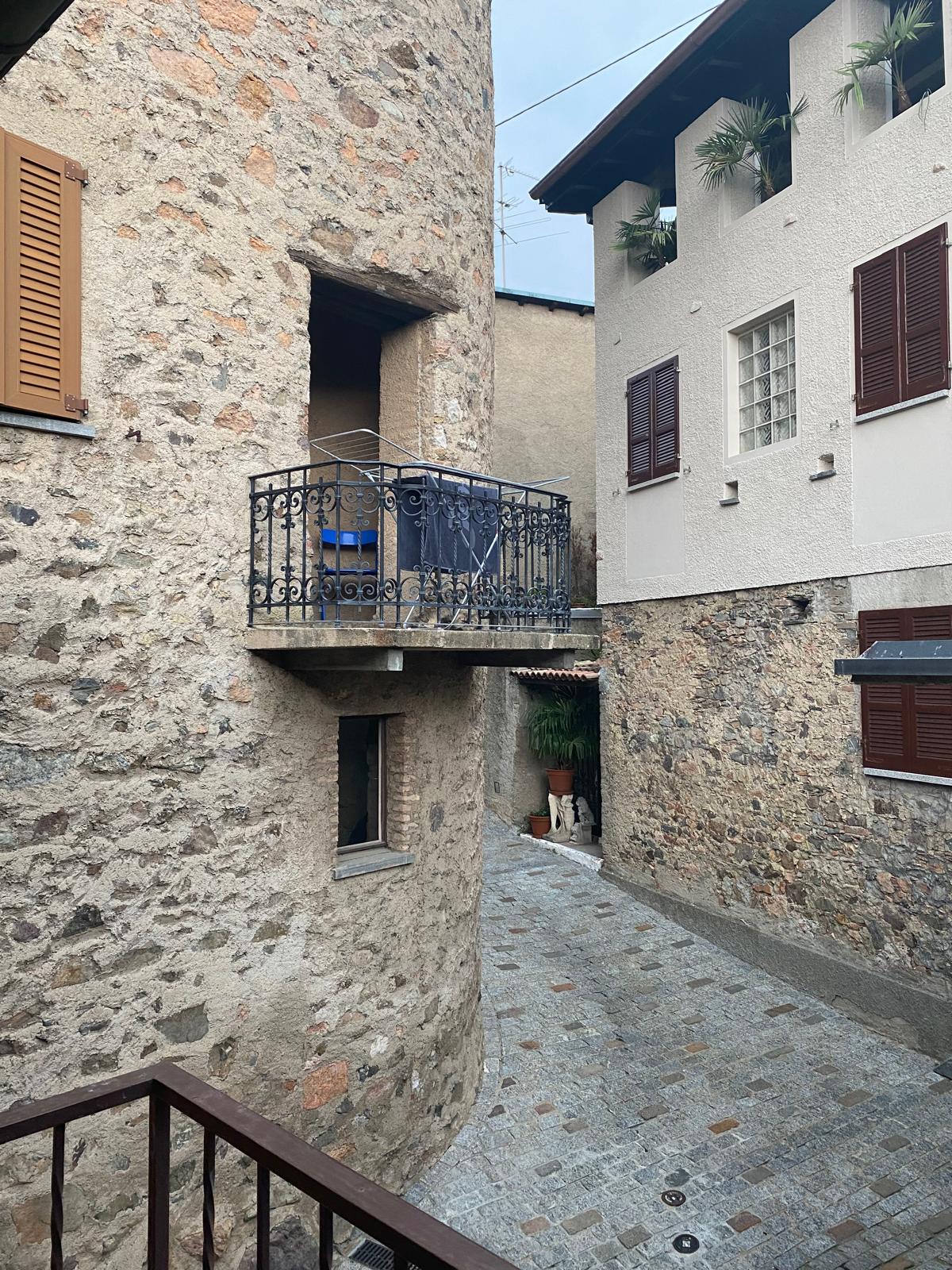 Stone walls, cobblestone street, balcony with wrought iron railing, brown shutters, small alley