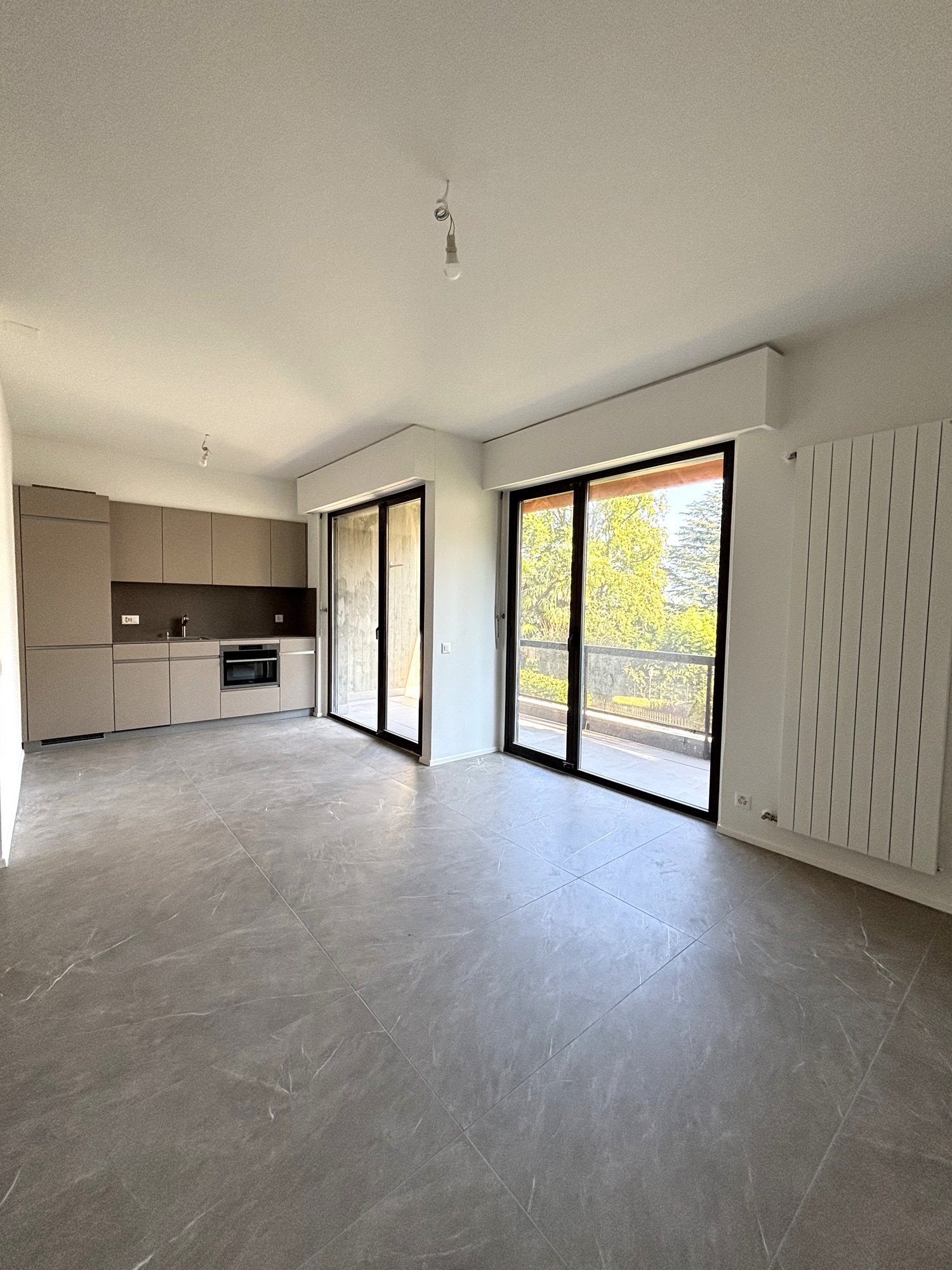 Open space kitchen-living room, large sliding glass doors to balcony, modern fixtures