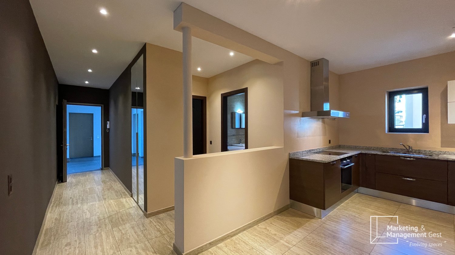 modern kitchen with granite countertops, stainless steel appliances, large sink, overhead lighting, and tiled floor.