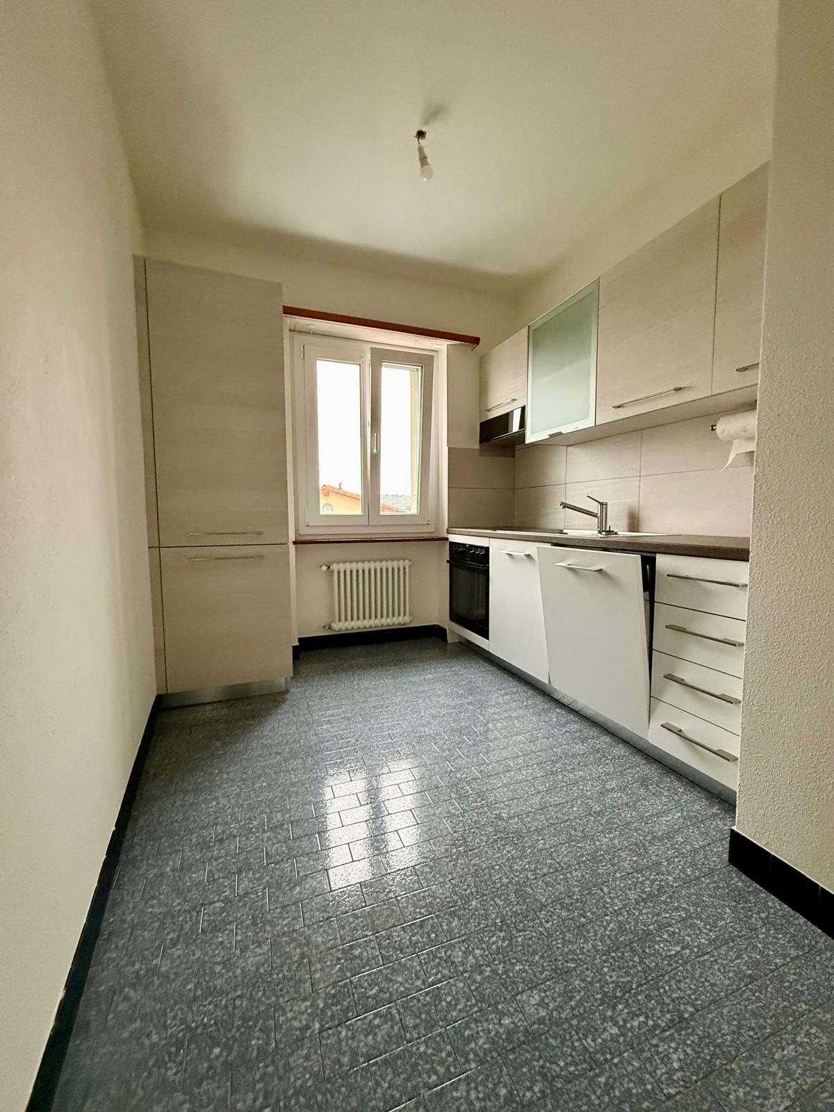 White kitchen with tile floor, white cabinetry, under cabinet lighting, window, stainless steel appliances