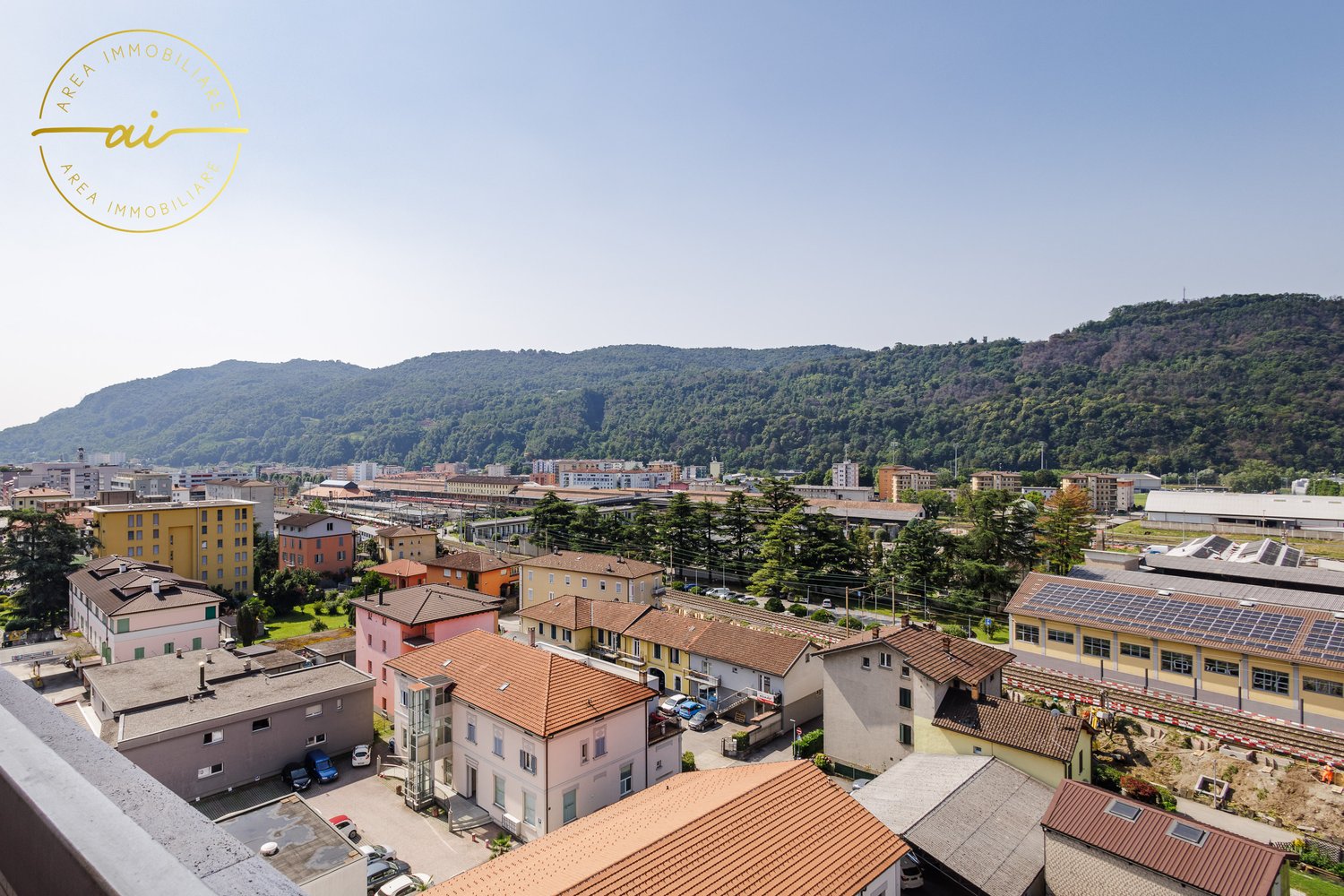 Cityscape: Many residential and commercial buildings, mountains in the background, solar panels