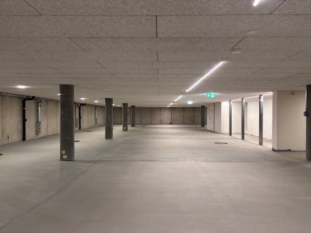 Empty parking lot with concrete floor, metal poles, and ceiling lights