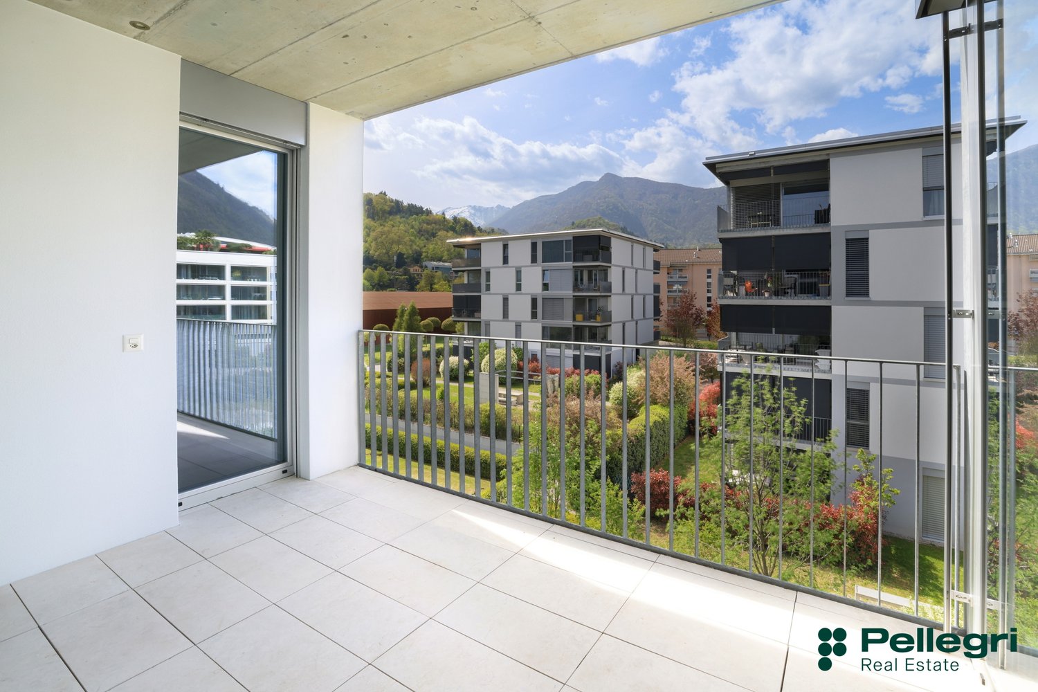 Balcony with railings, tiled floor, glass door, view of mountains and buildings