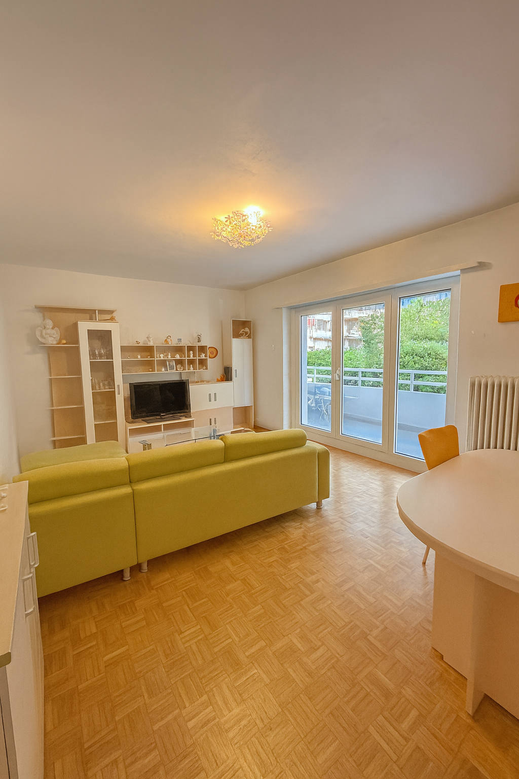 living room, green sofa, wooden flooring, glass balcony doors, TV