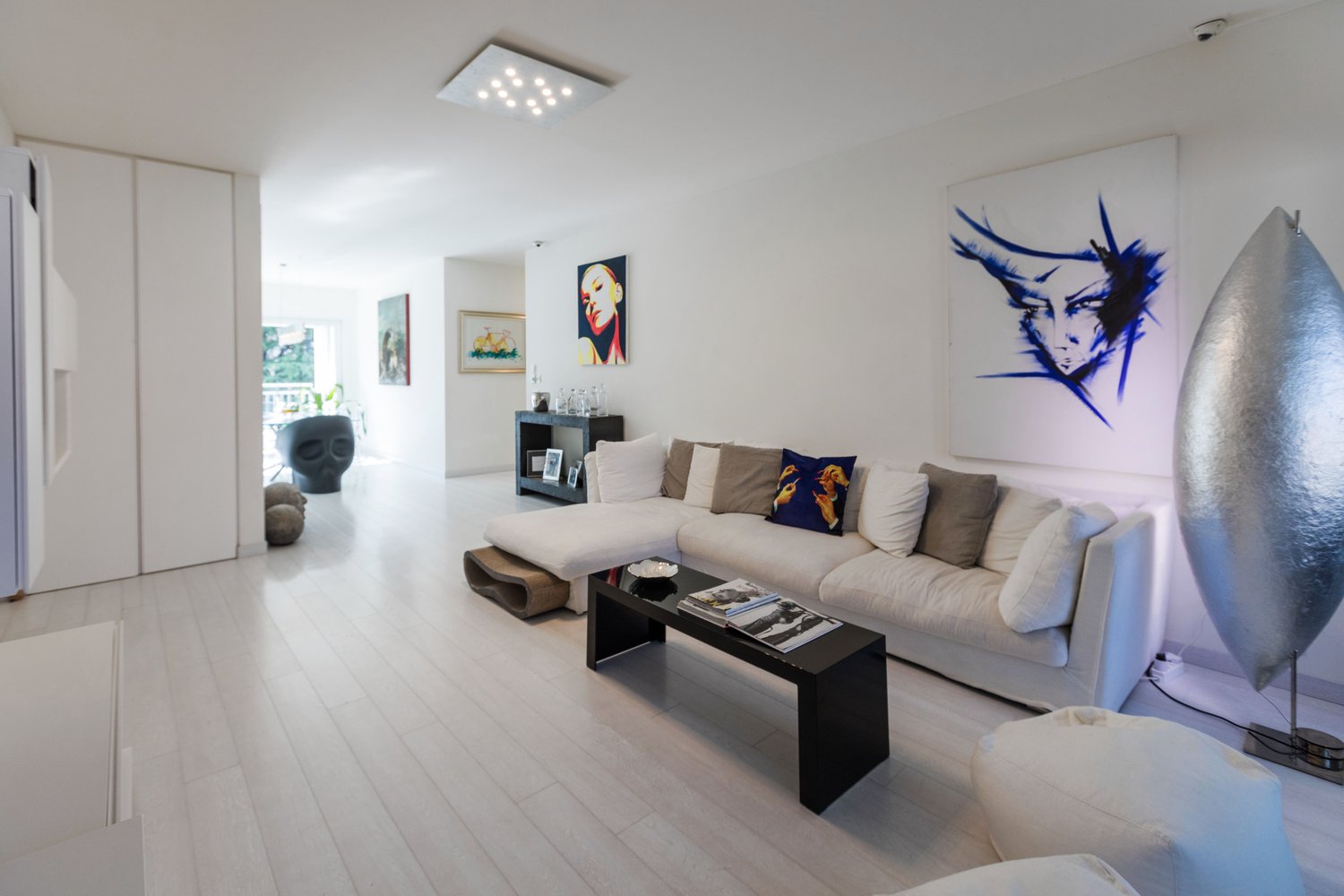white walls, white floor, white sofa, black coffee table, art pieces on the wall