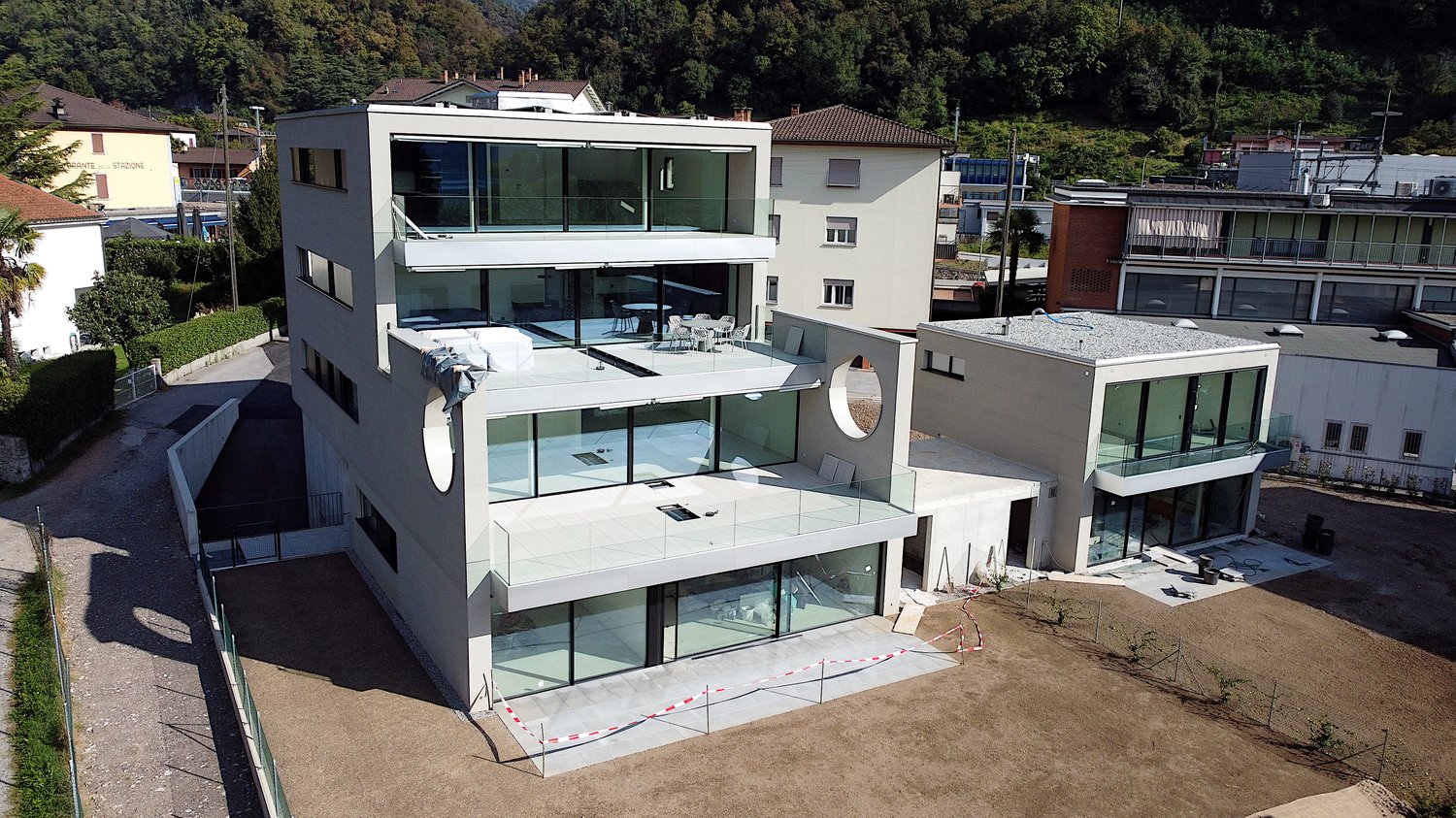 Modern building with glass walls, multiple balconies, roof terrace