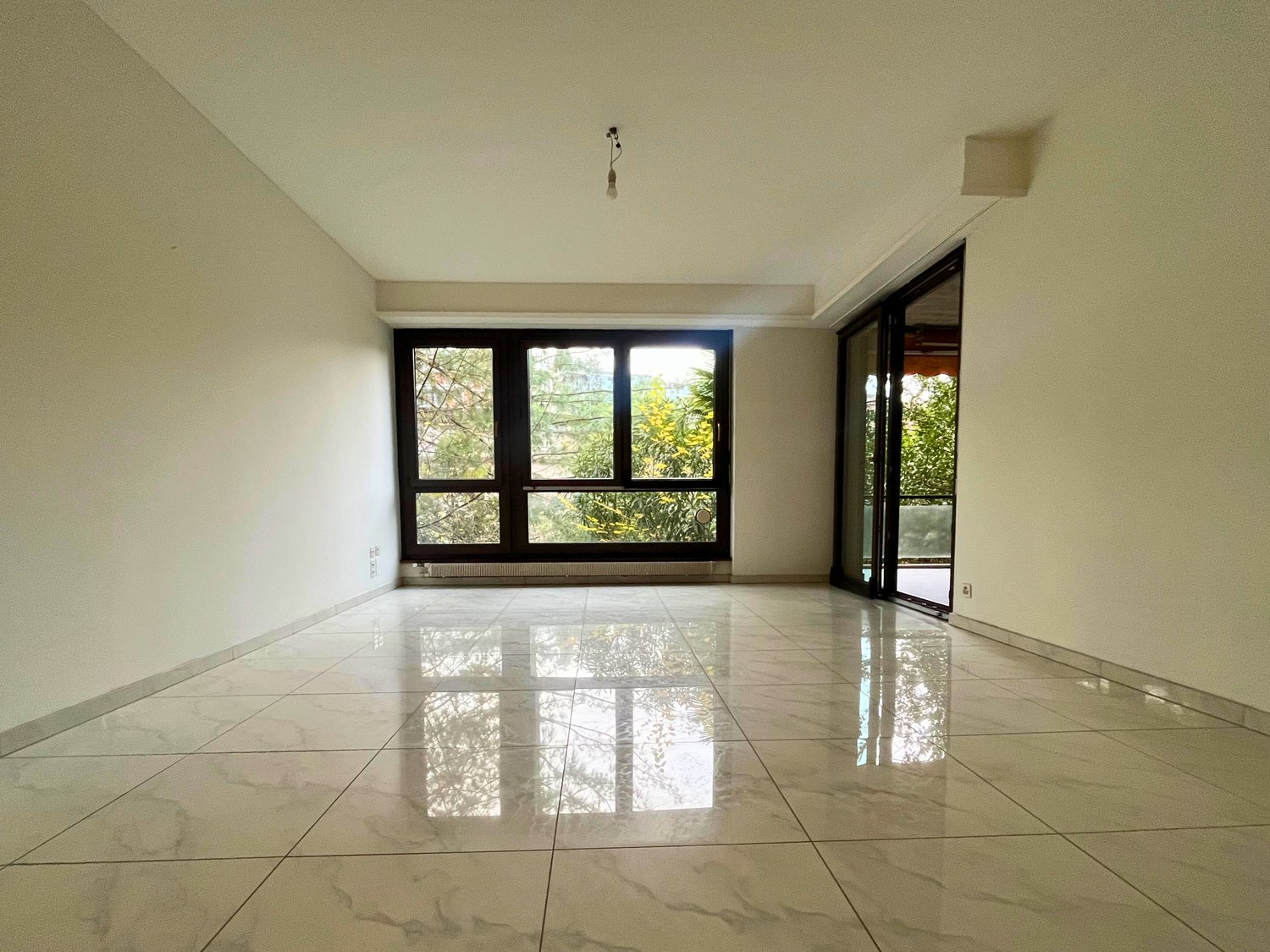 empty room, marble tiles, sliding glass doors leading to balcony, large windows