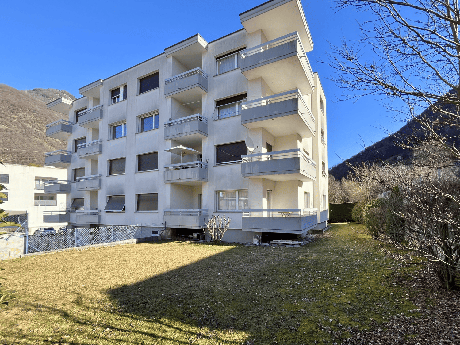 Apartment building with multiple balconies, modern architecture, surrounded by greenery, multiple floors