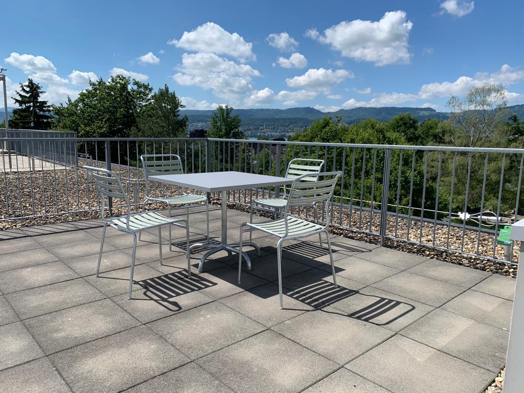 Outdoor table and chairs on a balcony with a view of the mountains