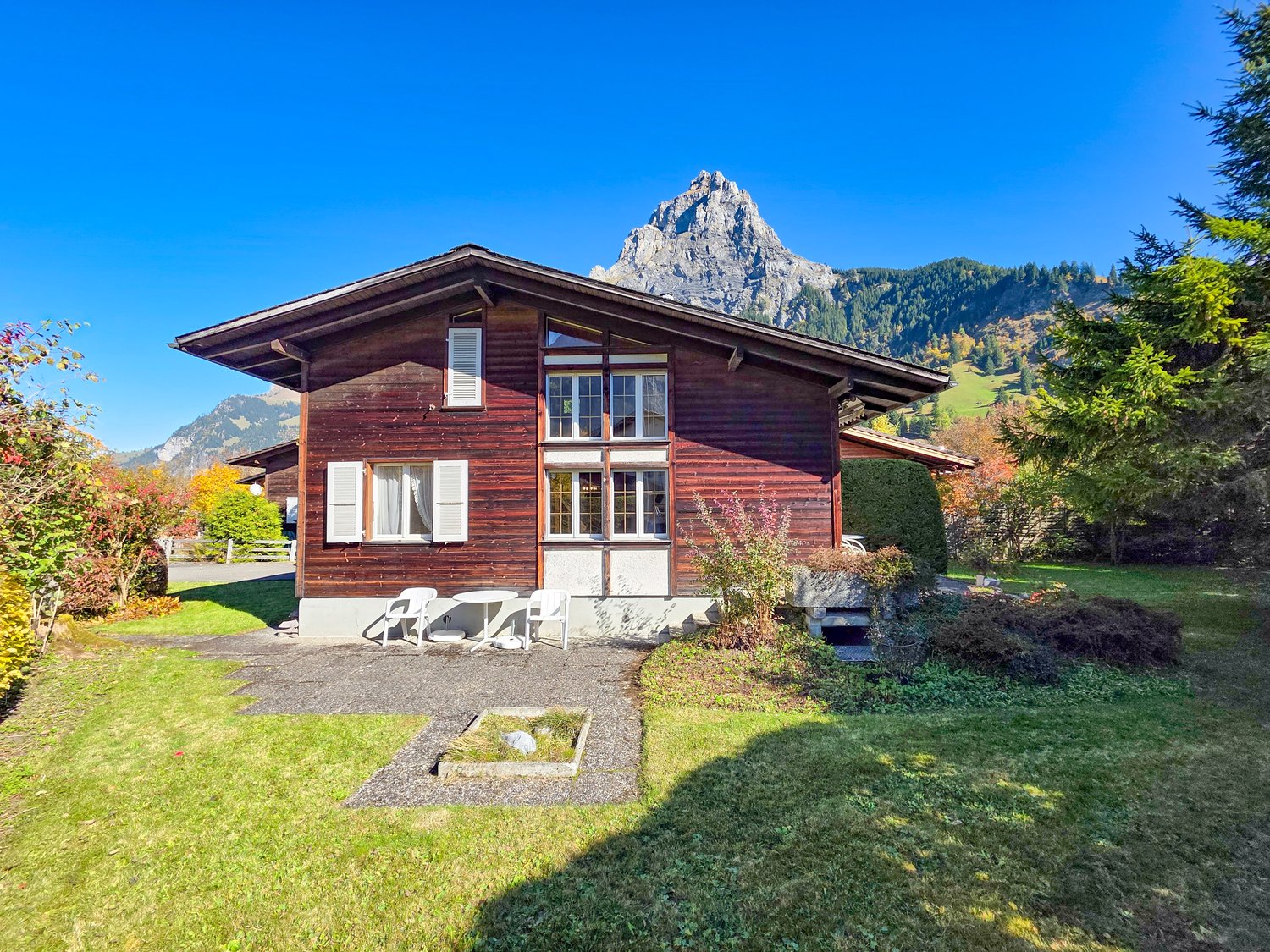 Traditional wooden chalet with mountain view, white trim, outdoor seating