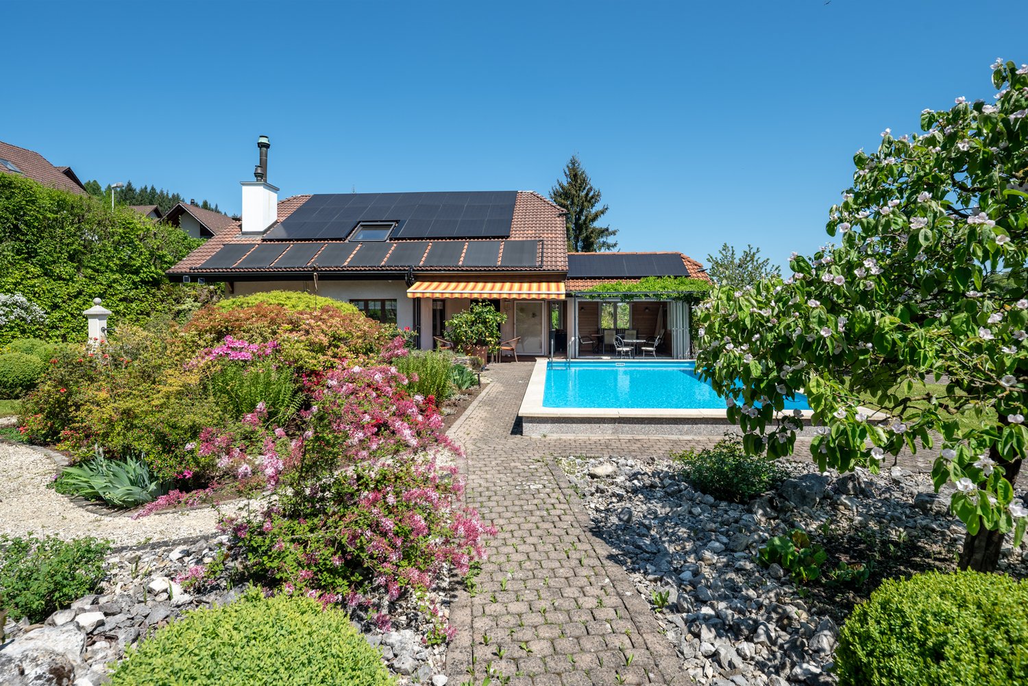 Charming house with solar panels on the roof, swimming pool, spacious garden, paved walkway, well-kept landscape