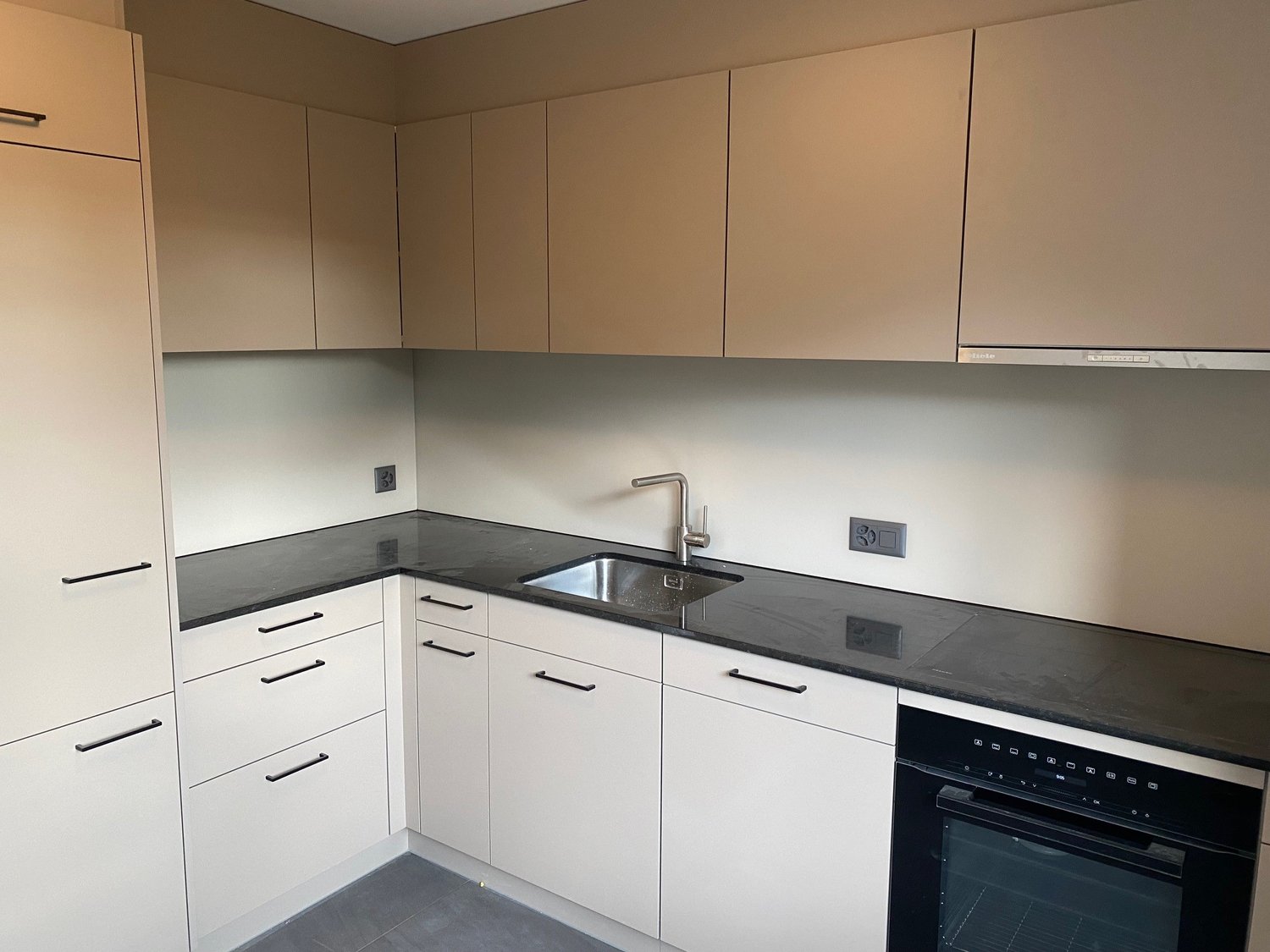 modern kitchen with white cabinets, black granite countertop, stainless steel sink, oven with glass door, power outlet on wall, drawers, modern faucet