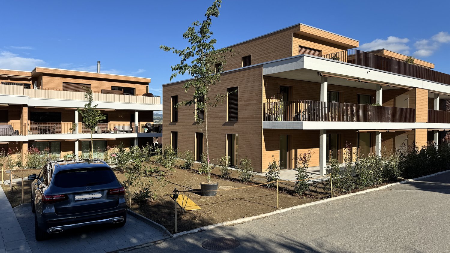 A two-story residential building made of wood, featuring balconies on the upper floor and a modern design with large windows.