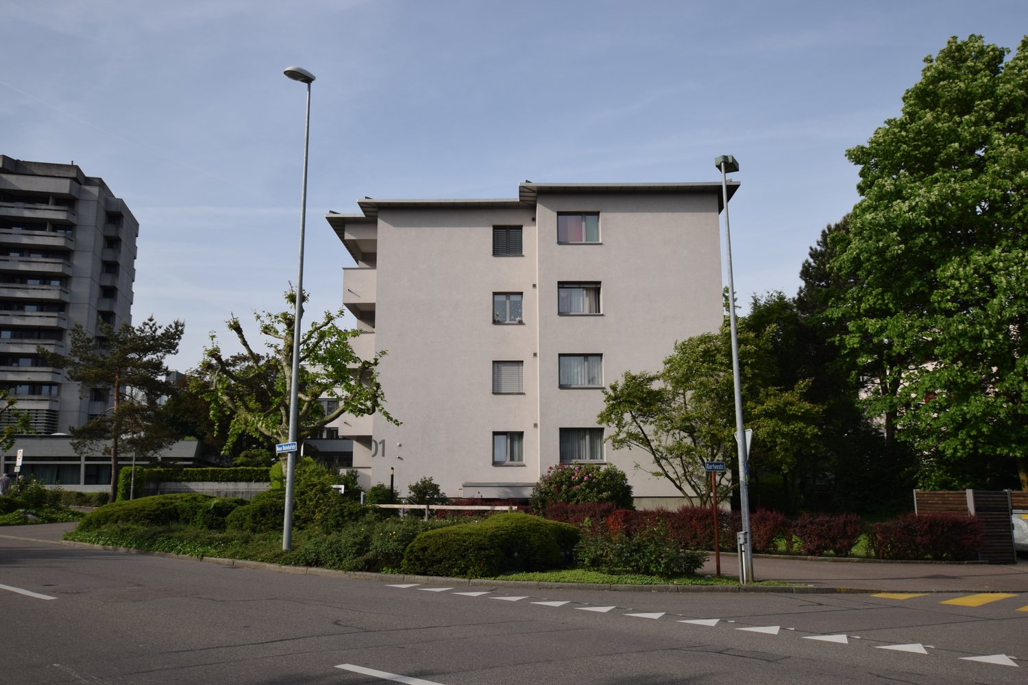 4 story building, white exterior, multiple windows, street, street lamps, street sign