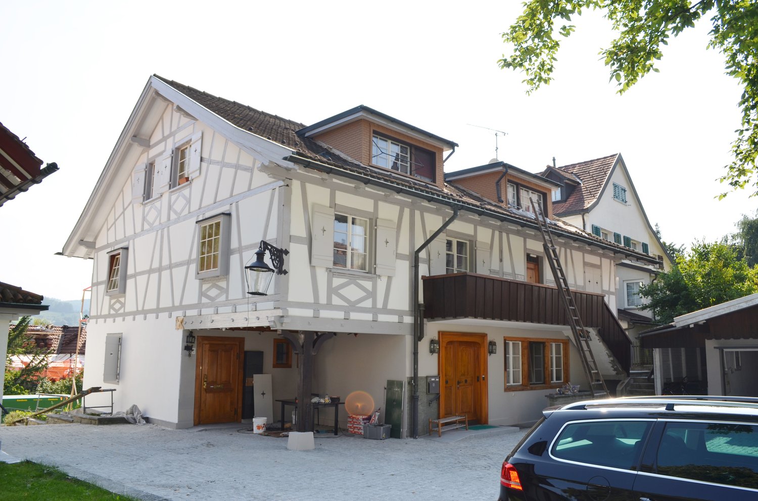 3 story house, raised ground floor, balcony, double doors, two garages, trees