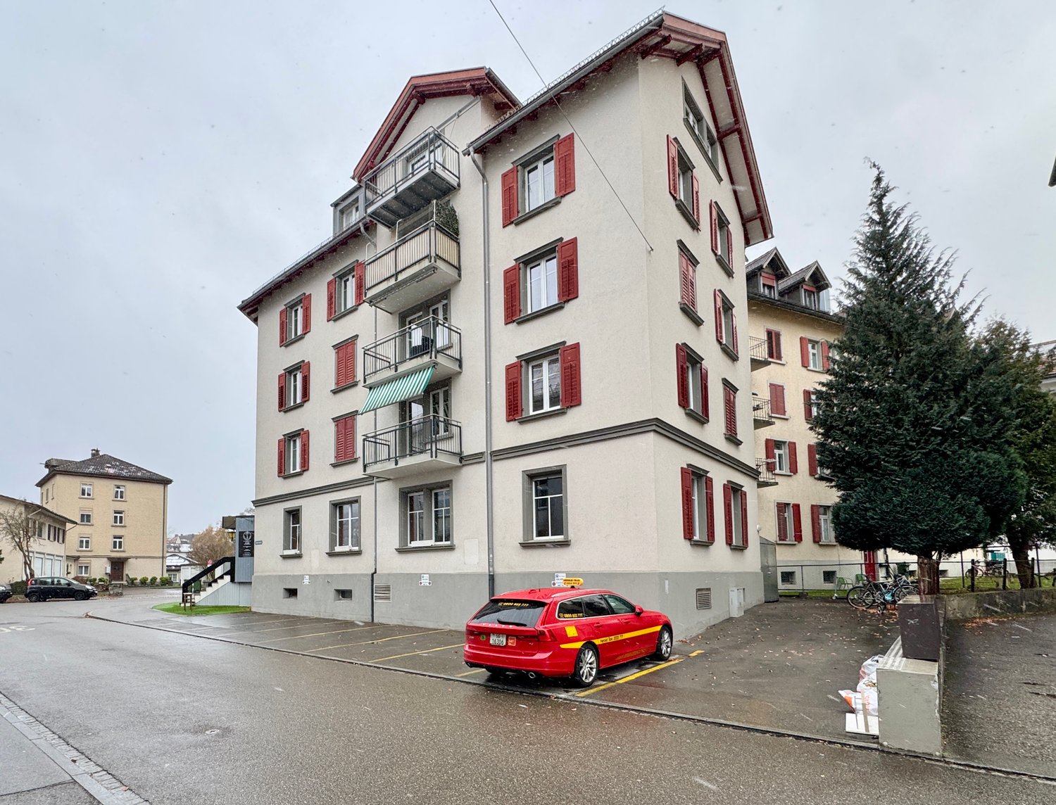 Multi-story building with balconies and parking spaces in front.