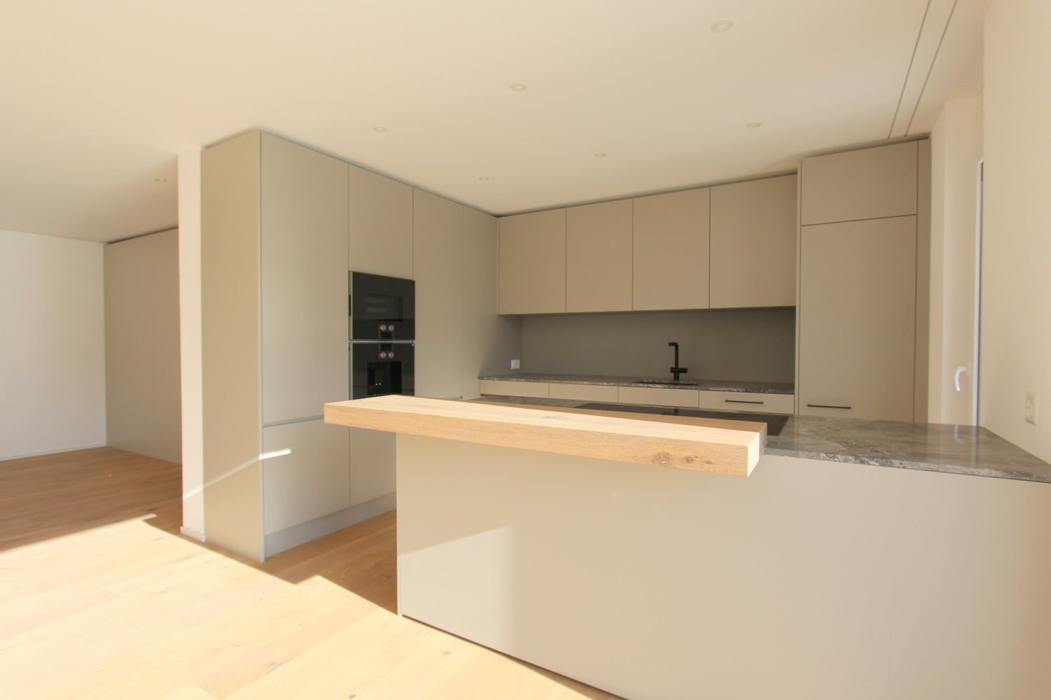 Open kitchen with granite countertop, built-in oven, island counter with wooden top, stainless steel faucet, modern cabinets