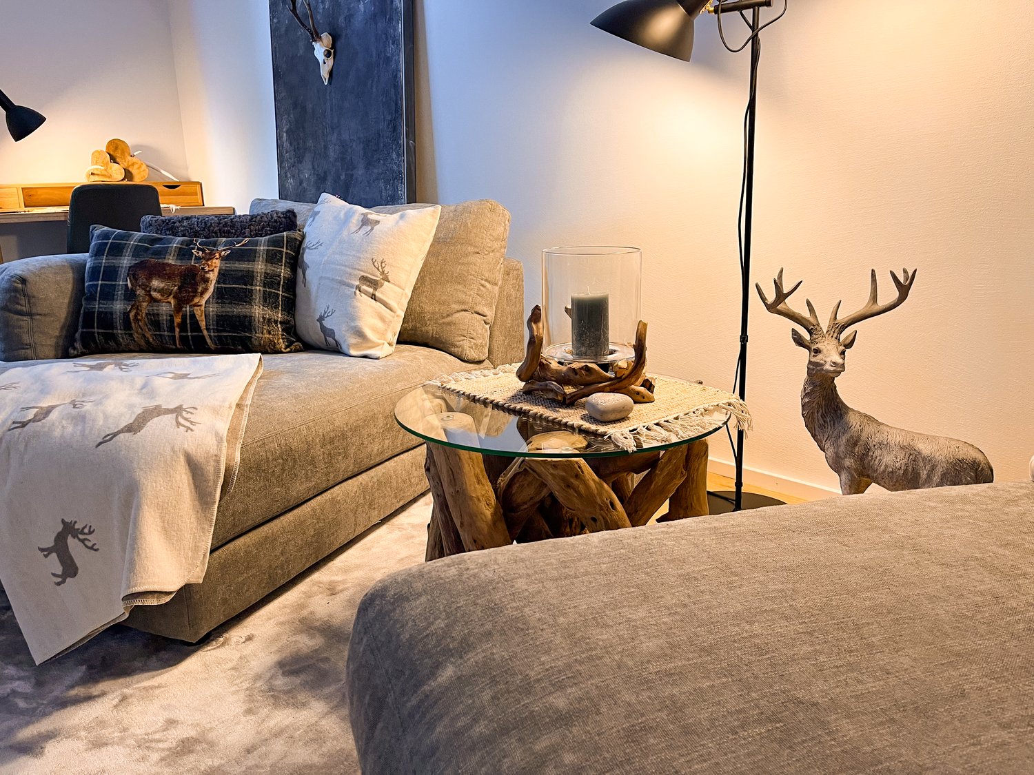 living room with couch, coffee table, desk, lamps, and a deer statue