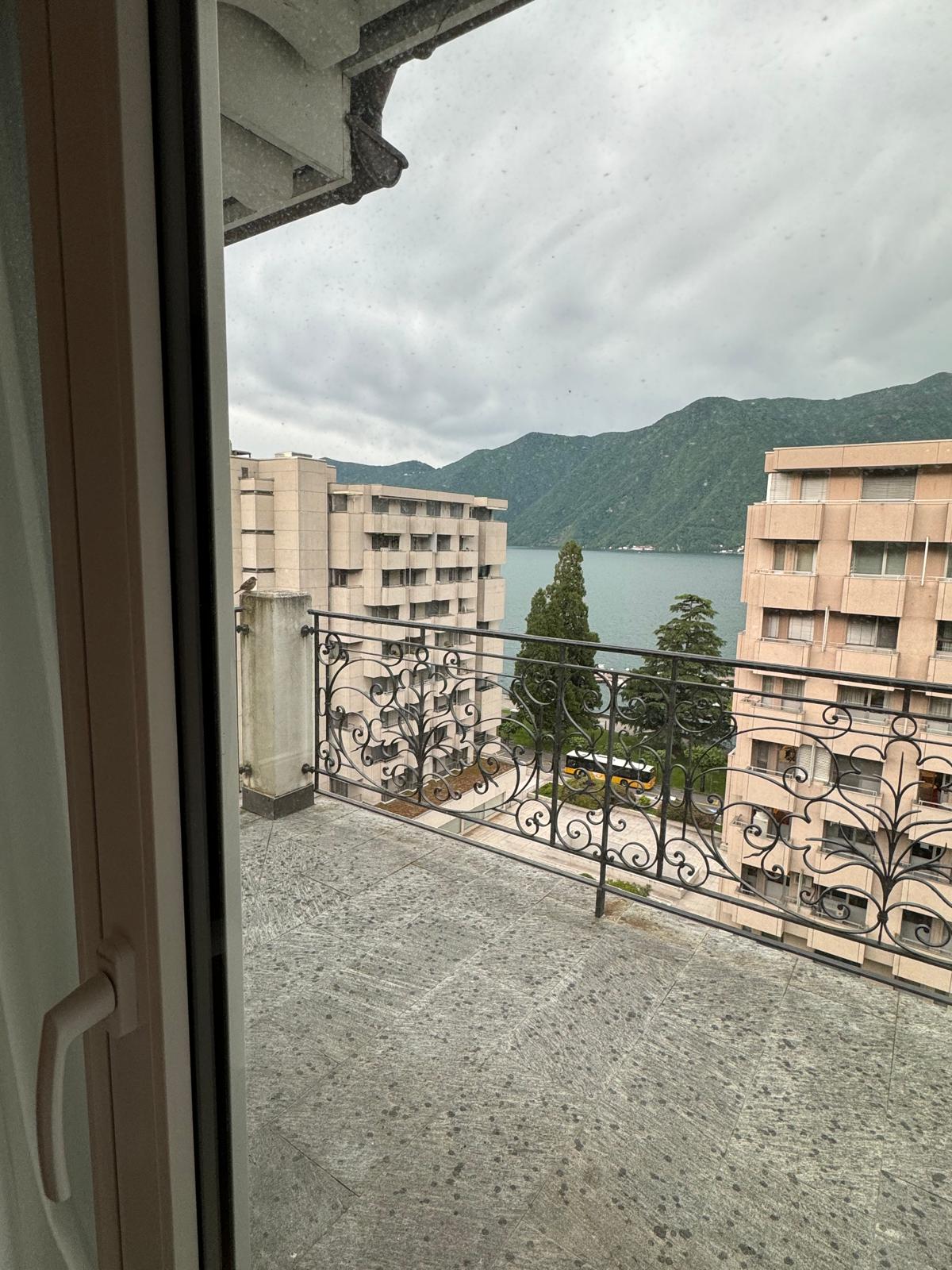 outdoor balcony with stone floor, wrought iron railing, view of lake and mountains