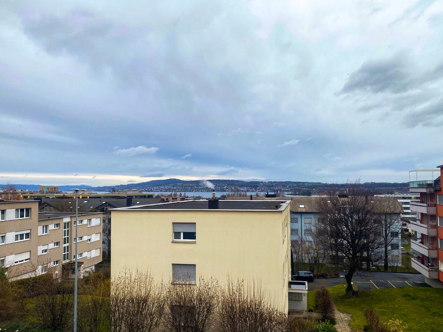 multiple story residential building in urban setting, river and mountains in the distance