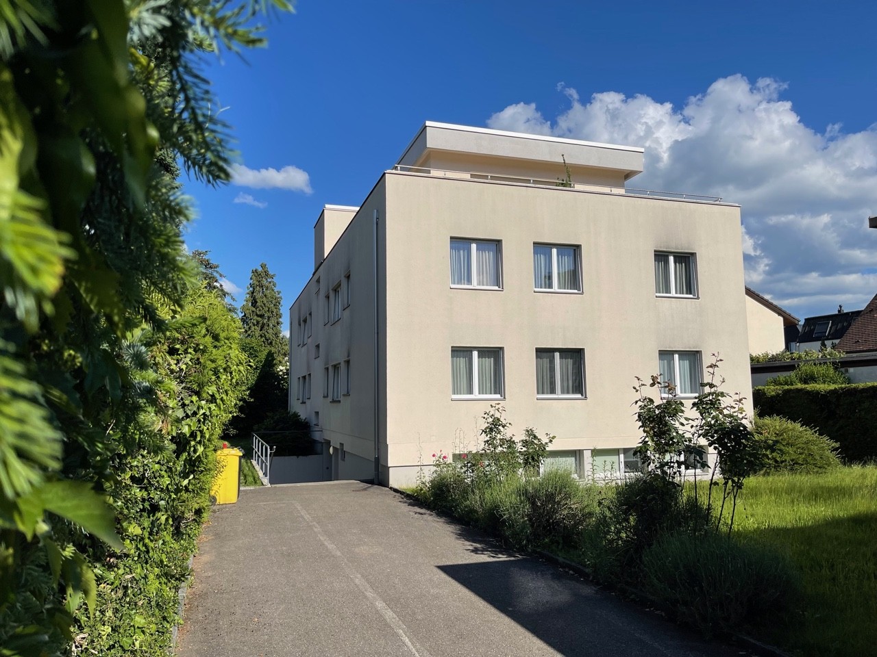 4 story building, beige color, several windows, balcony on the top floor