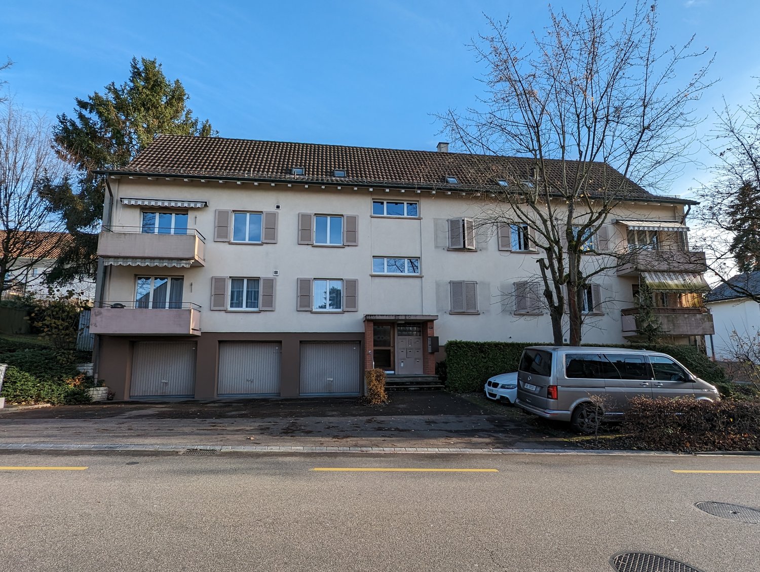 4-story apartment building, beige and brown, brown roof, large balconies, several garages