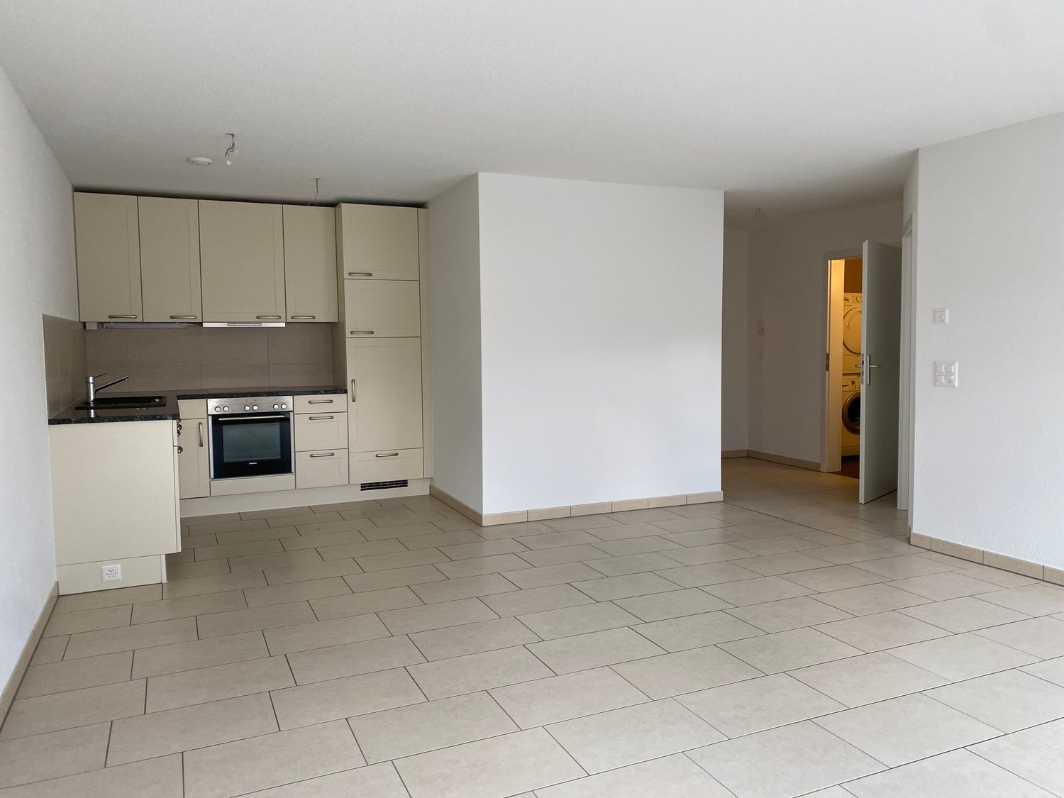 Modern kitchen with white cabinets, black countertops, stainless steel sink, oven, microwave, and washing machine