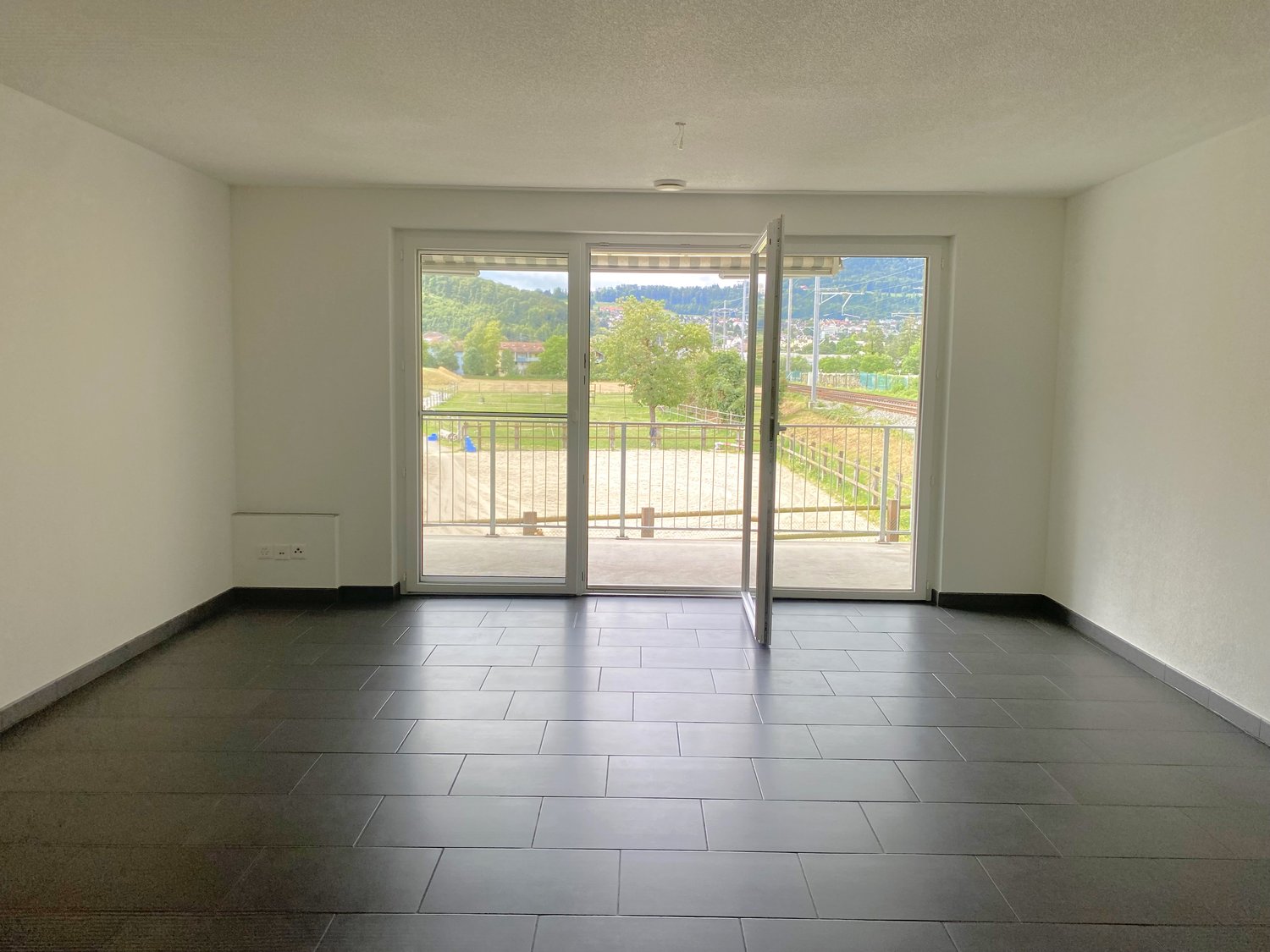 empty room, sliding glass doors leading to balcony, tiled floor, white walls