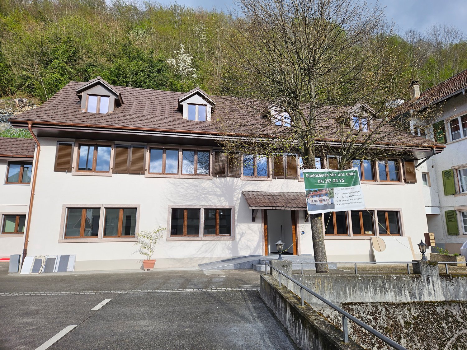 Detached house with a brown roof, several windows, a beige exterior, a ramp, and a few plants.