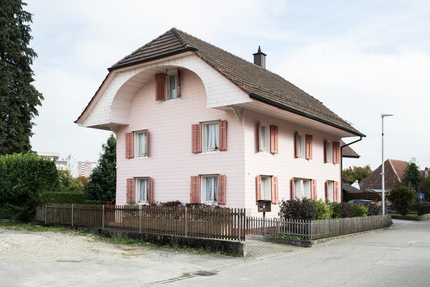pink house, brown roof, brown windows, wooden fence