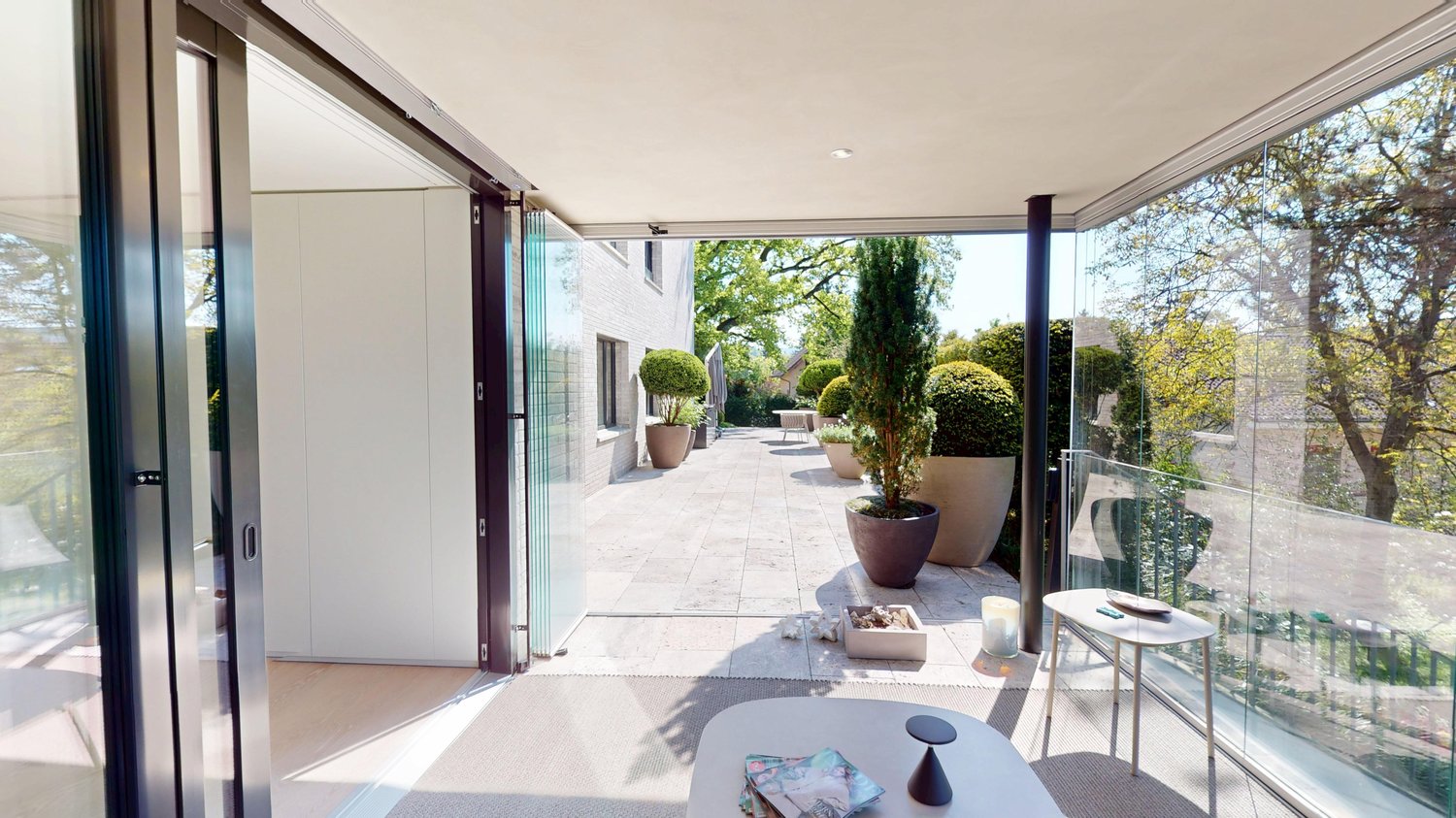large balcony, large windows, carpet, two tables, magazines