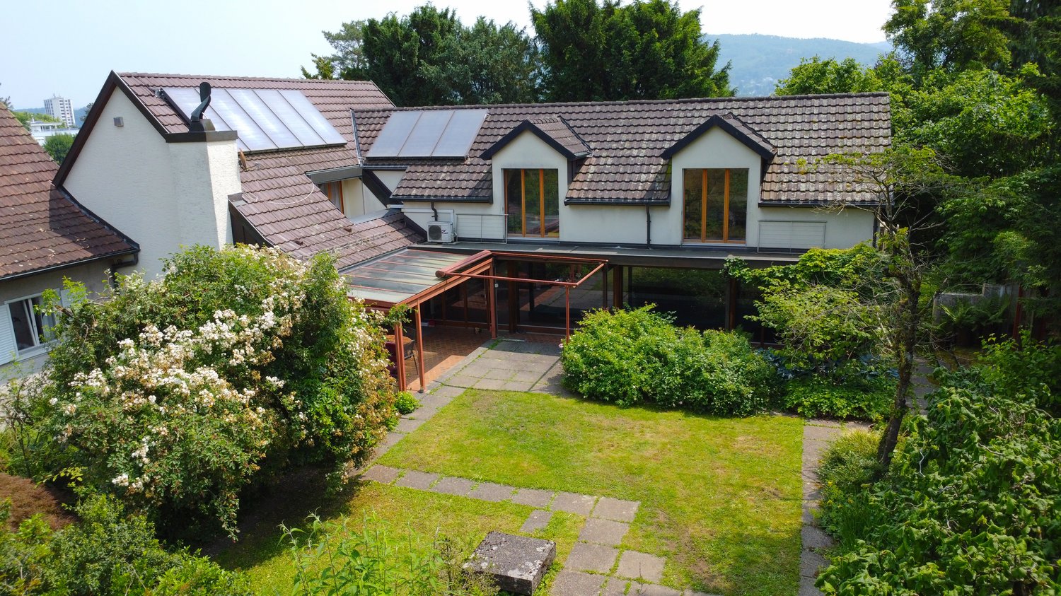 2-story house, brown roof, glass windows, glass patio, small garden