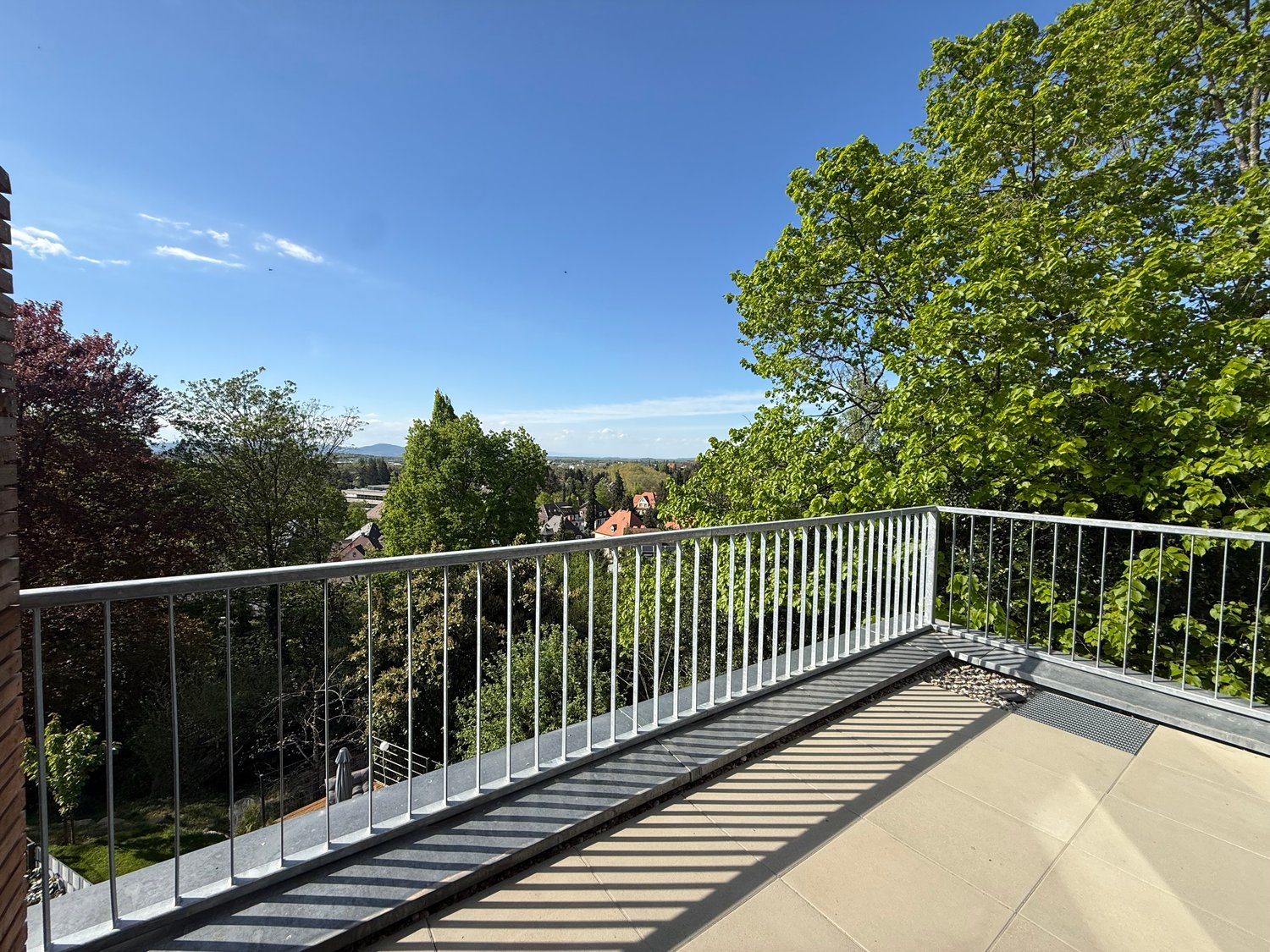 Metal railing, tiled floor, view of trees and houses