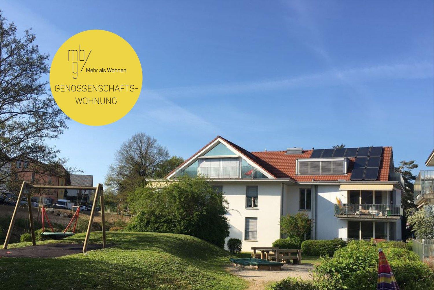 large modern house, solar panels on roof, balcony, surrounded by green garden with swing set, red roof