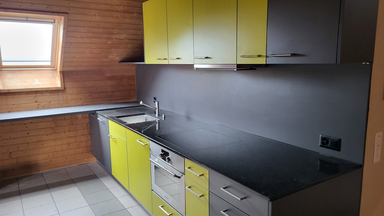 yellow and grey cabinets, black countertop, oven, sink, faucet, power outlet