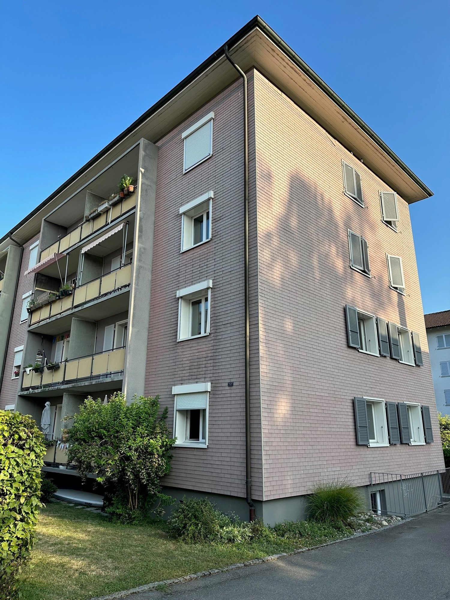 4-story apartment building with balconies, brick walls, many windows, central drain pipe