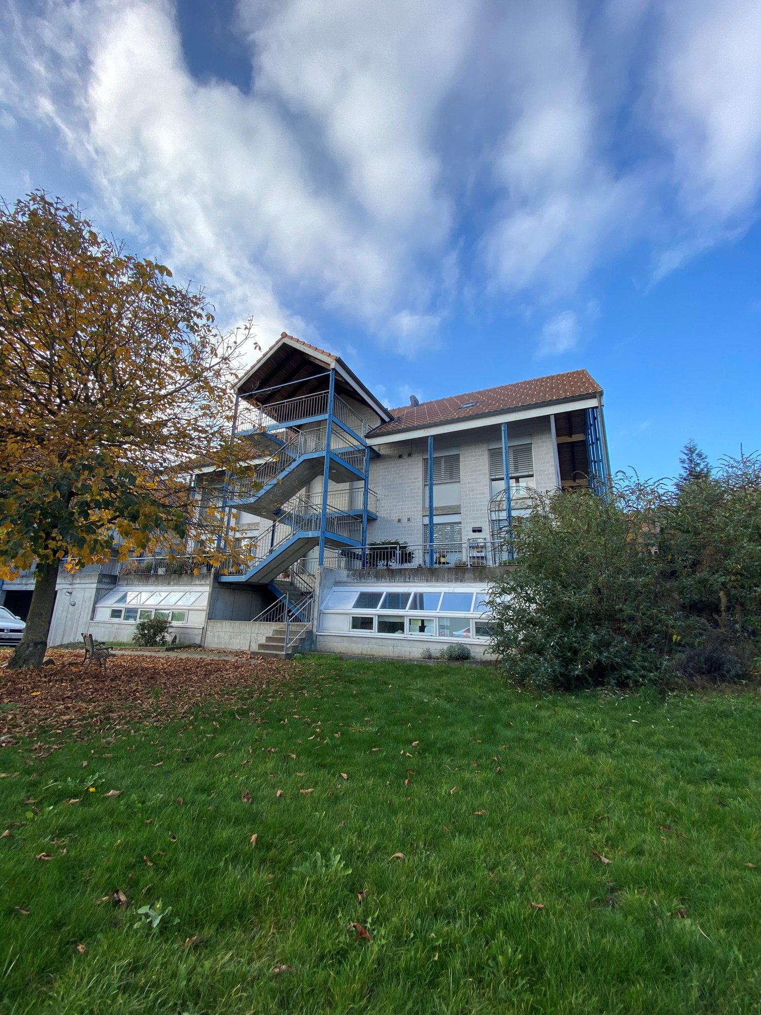 2 story house, white walls, blue pillars, stairs, balcony, garden