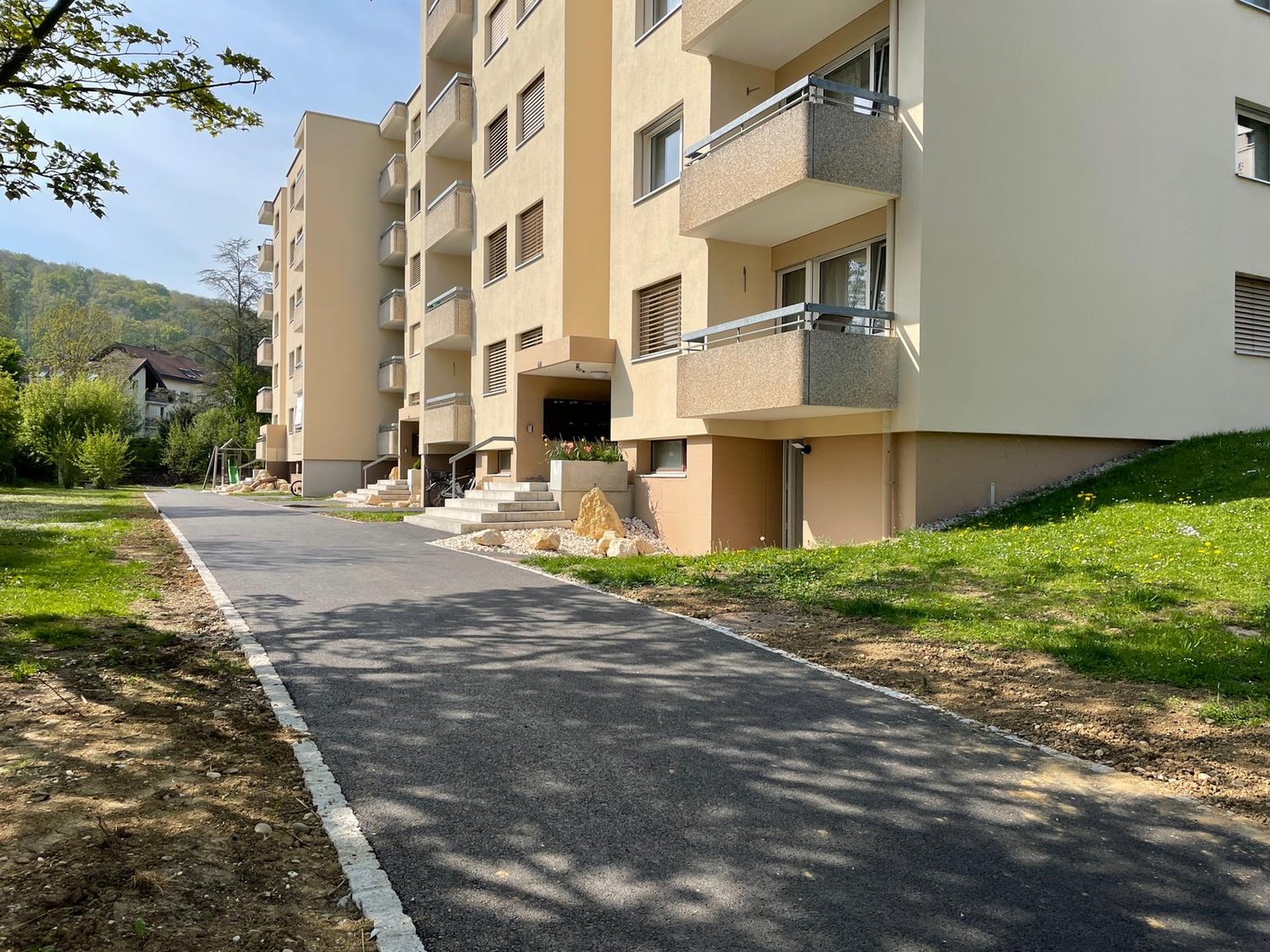 apartment building, multiple floors, balconies, paved driveway, grass area