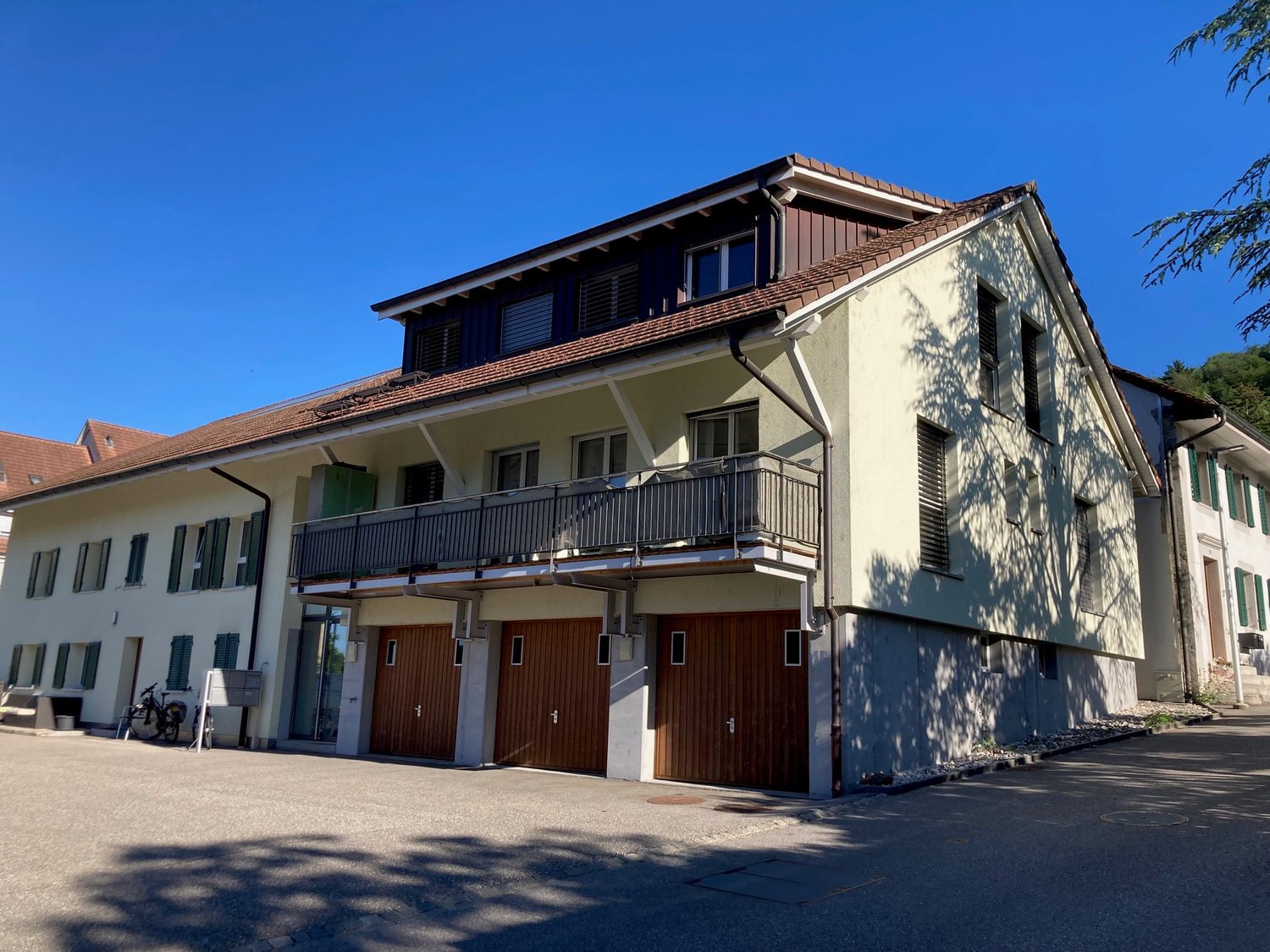 2 story building, brown roof, white walls, balcony, double garages