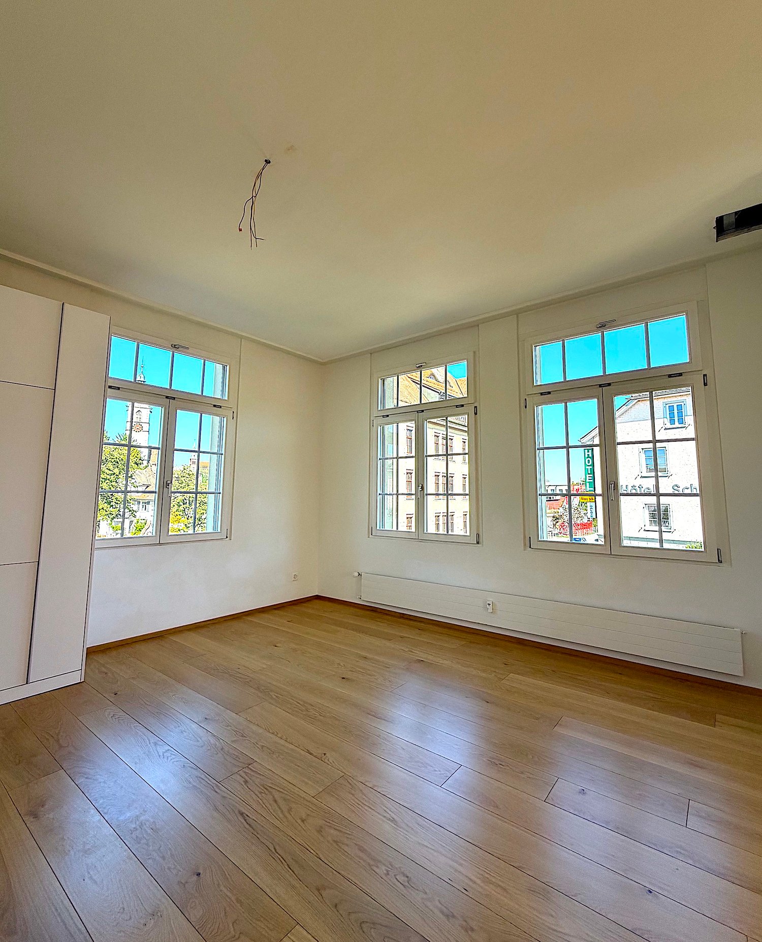 empty room, three windows, wooden floor, white walls