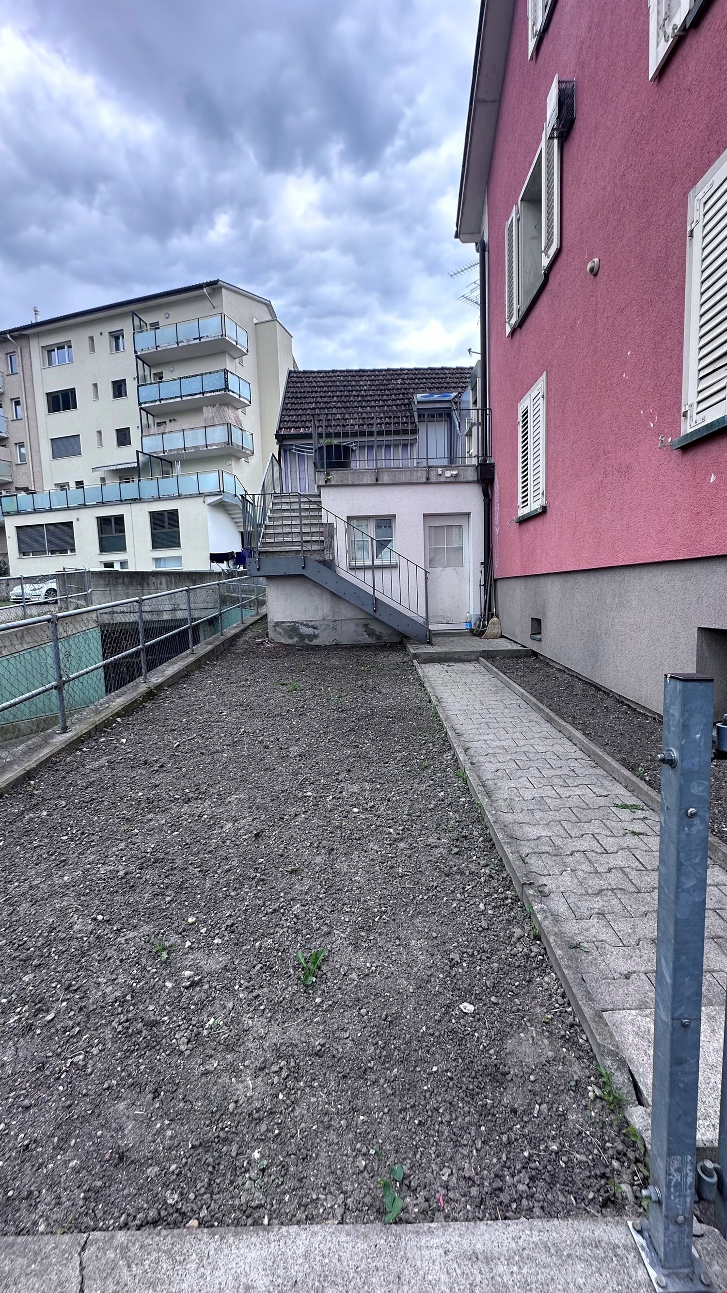 Backyard area, empty, pathway, buildings on either sides