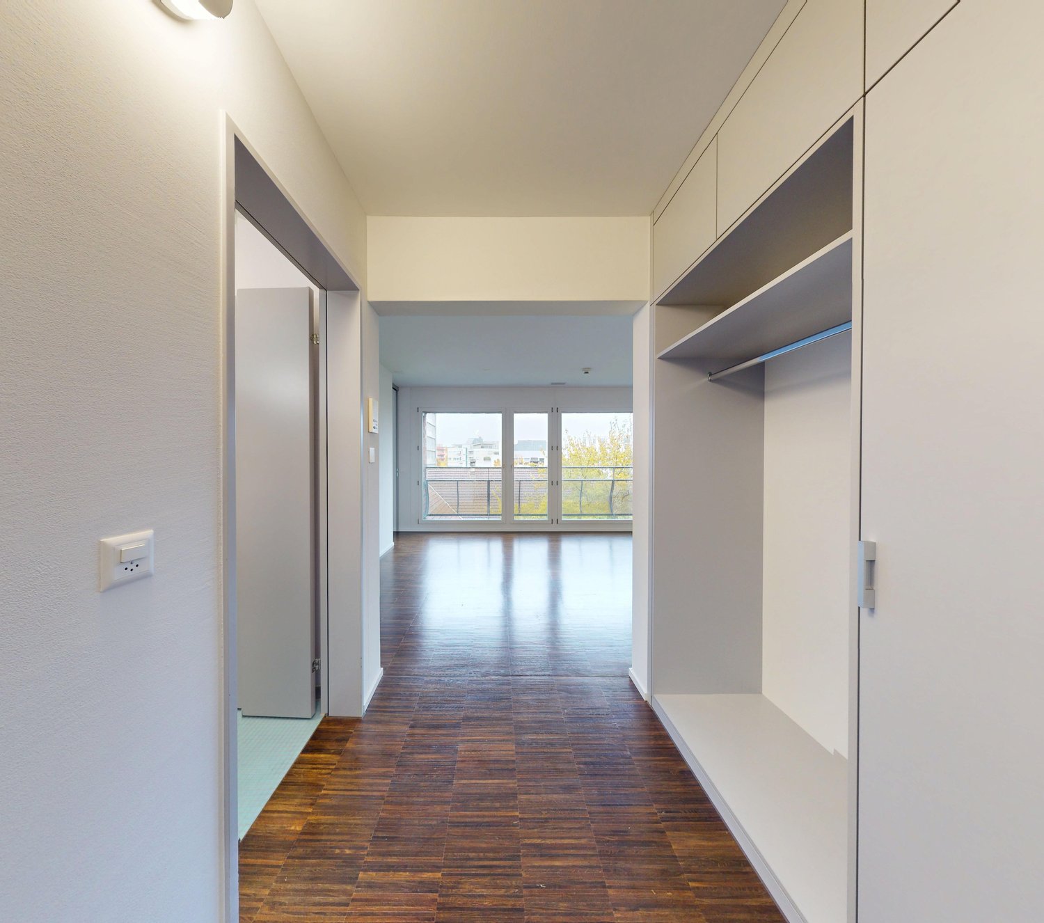 Empty hallway with wood floor, large windows leading to balcony