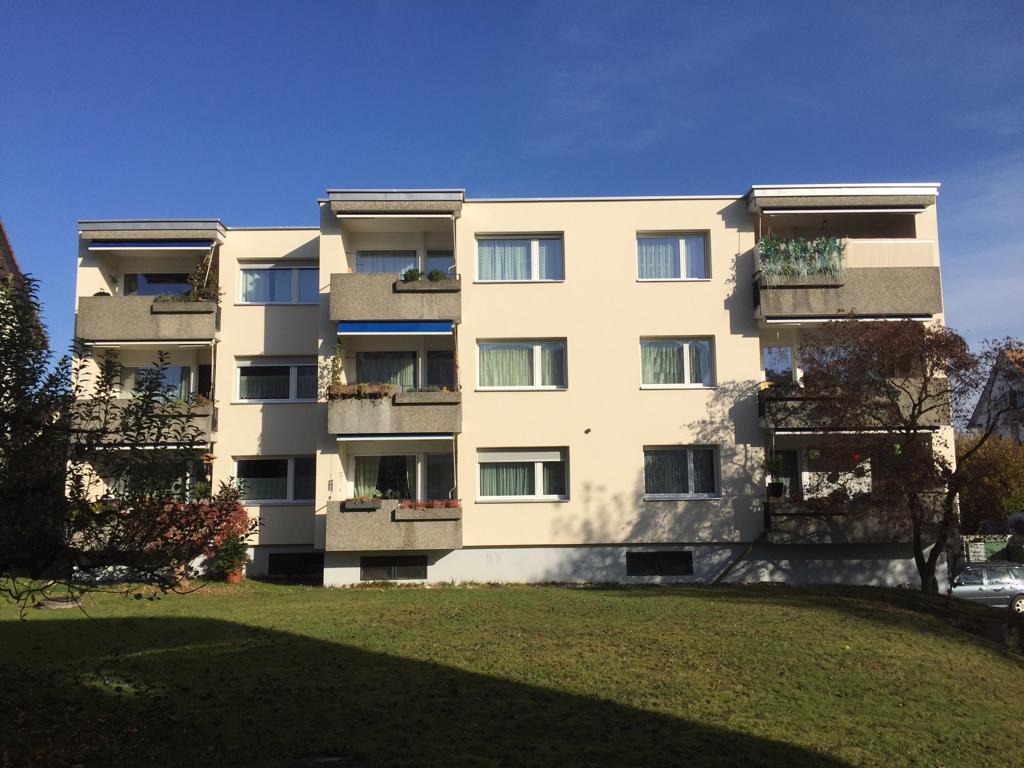 multi-storey building, cream-colored exterior, multiple balconies, glass windows, plants on balconies