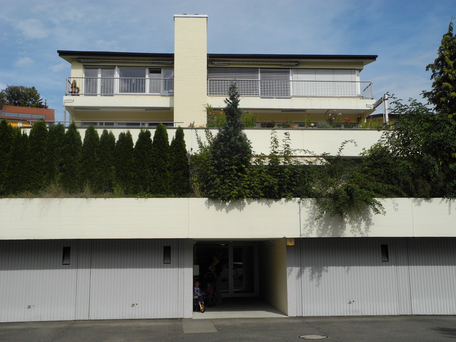 2 story house, white exterior, raised ground floor, garage, balcony, green roof