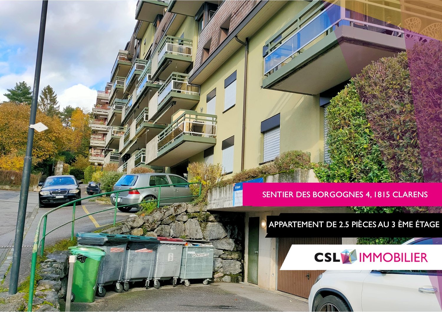 Multi-story apartment building with balconies, located in a residential area with trees and vegetation. The building has a sign indicating an apartment for rent on the 3rd floor.