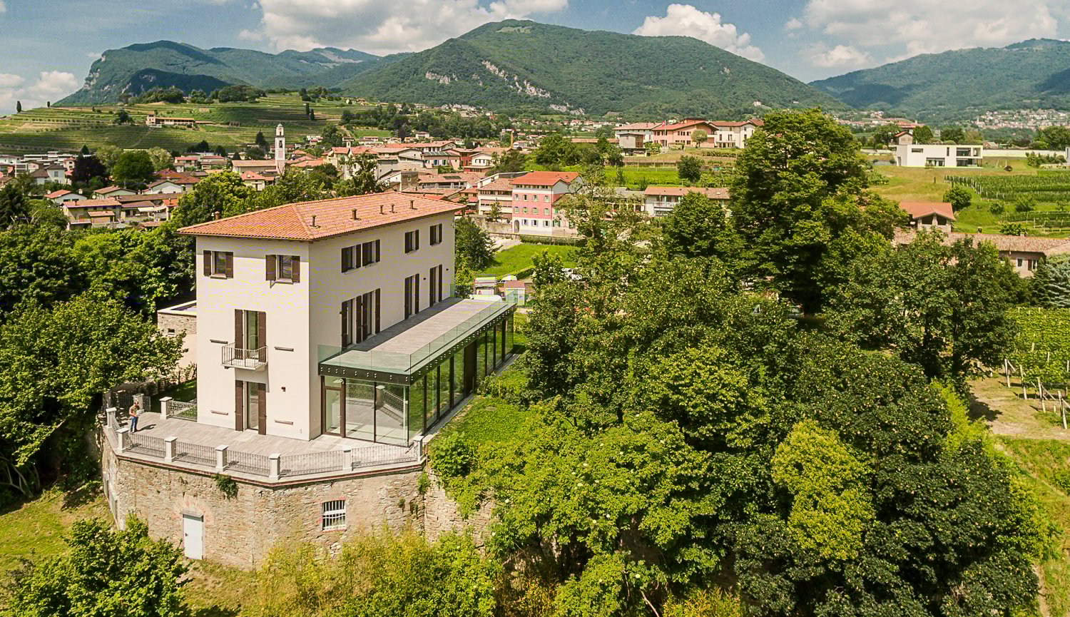 large white house with glass roof on raised ground, balcony with railings, panoramic view