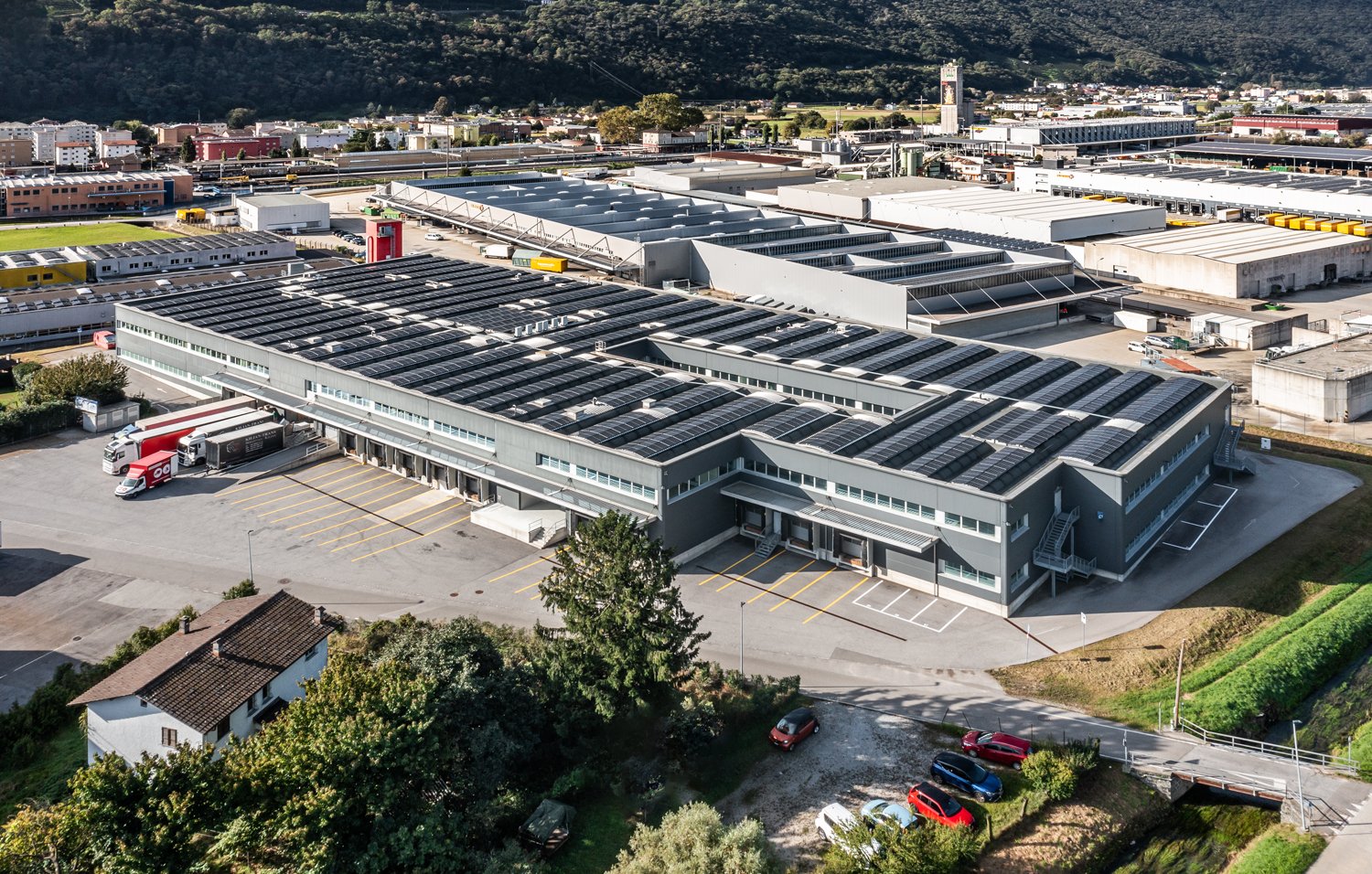 industrial building with solar panels, parking lot, and surrounded by greenery