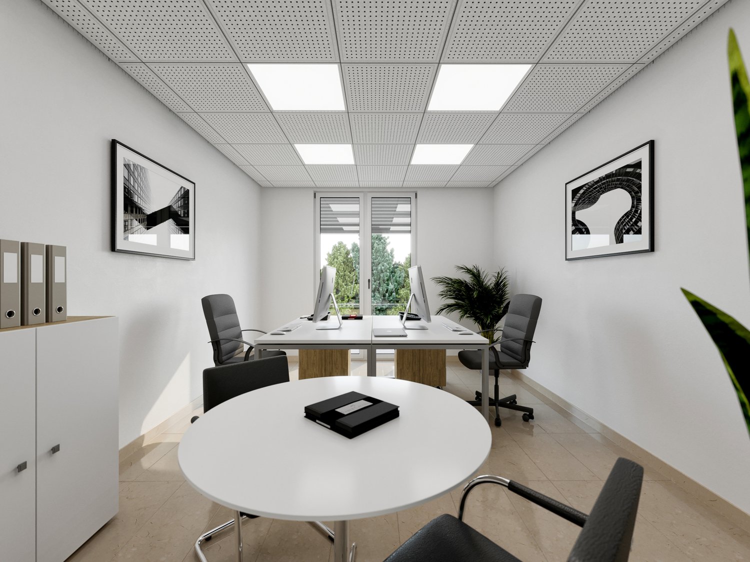 This image shows a modern and minimalist office space. The room has a white ceiling with recessed lighting panels, white walls, and a tiled floor. There is a large round white table in the center of the room, surrounded by black office chairs. Two framed