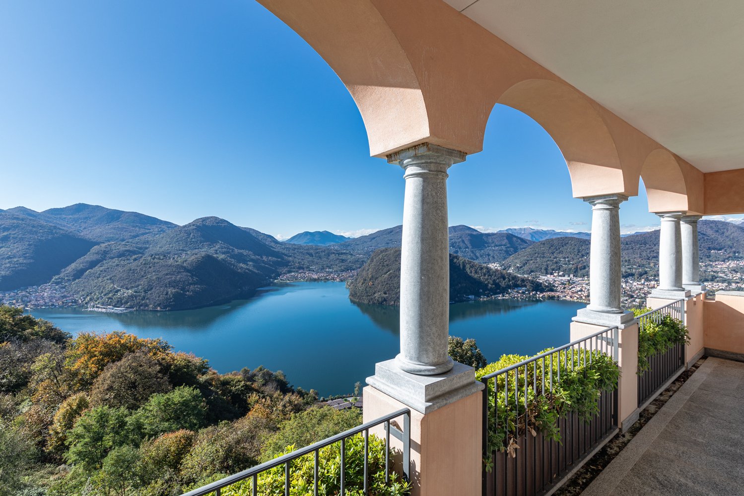 Arched balcony with railing overlooking lake and mountains